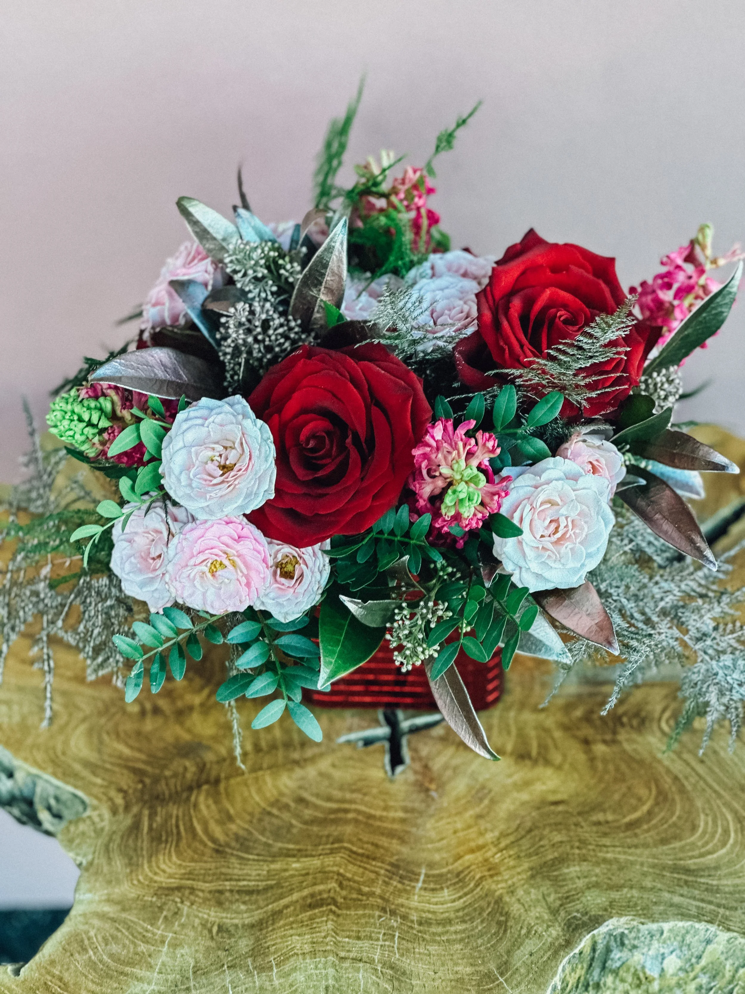 Small Valentine’s Day flower arrangement with red roses, pink tulips, blue accents, and fresh greenery in a red cube vase, available for Edmonton St Albert and Sturgeon County flower delivery.