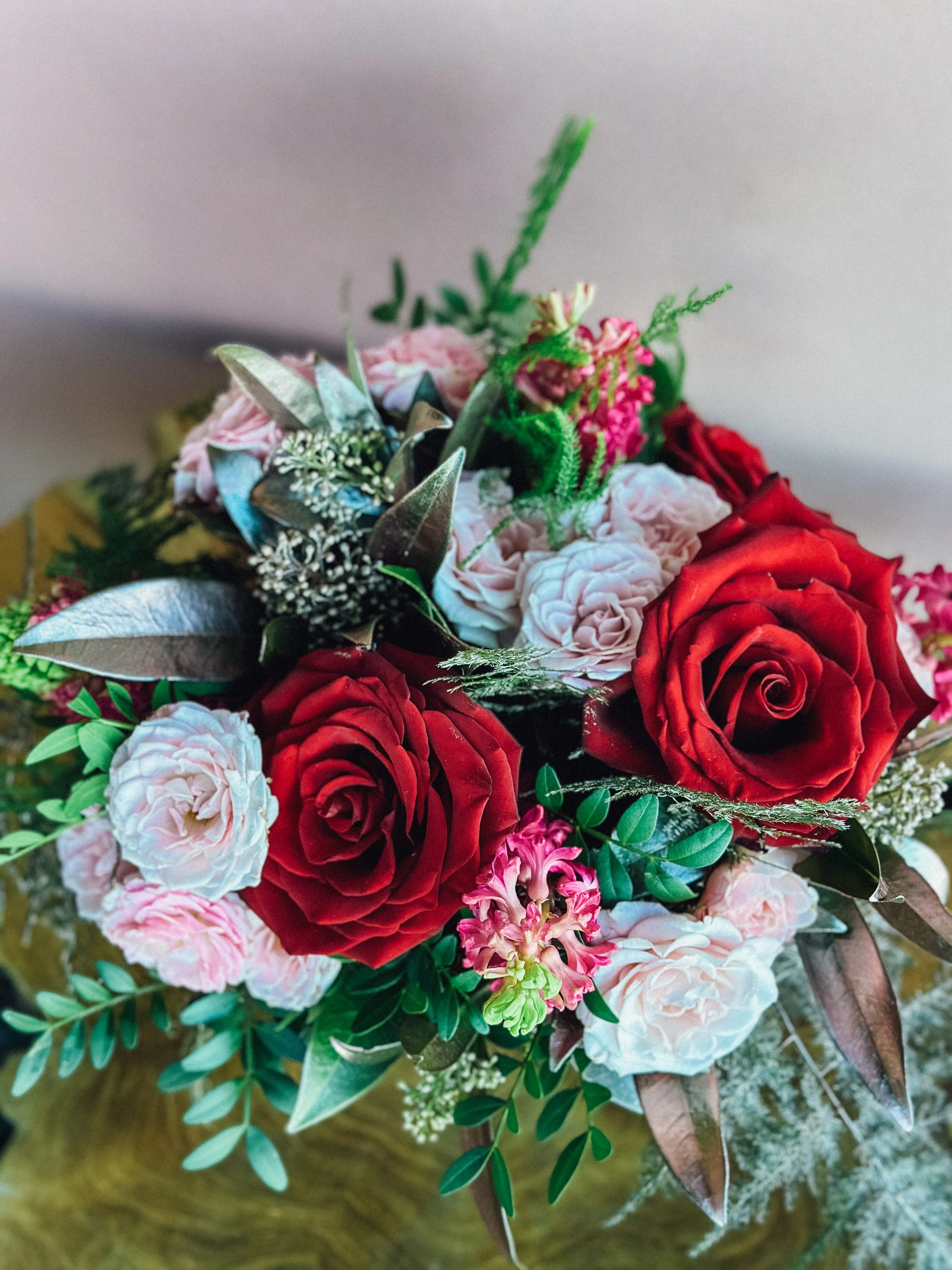 Small Valentine’s Day flower arrangement with red roses, pink tulips, blue accents, and fresh greenery in a red cube vase, available for Edmonton St Albert and Sturgeon County flower delivery.