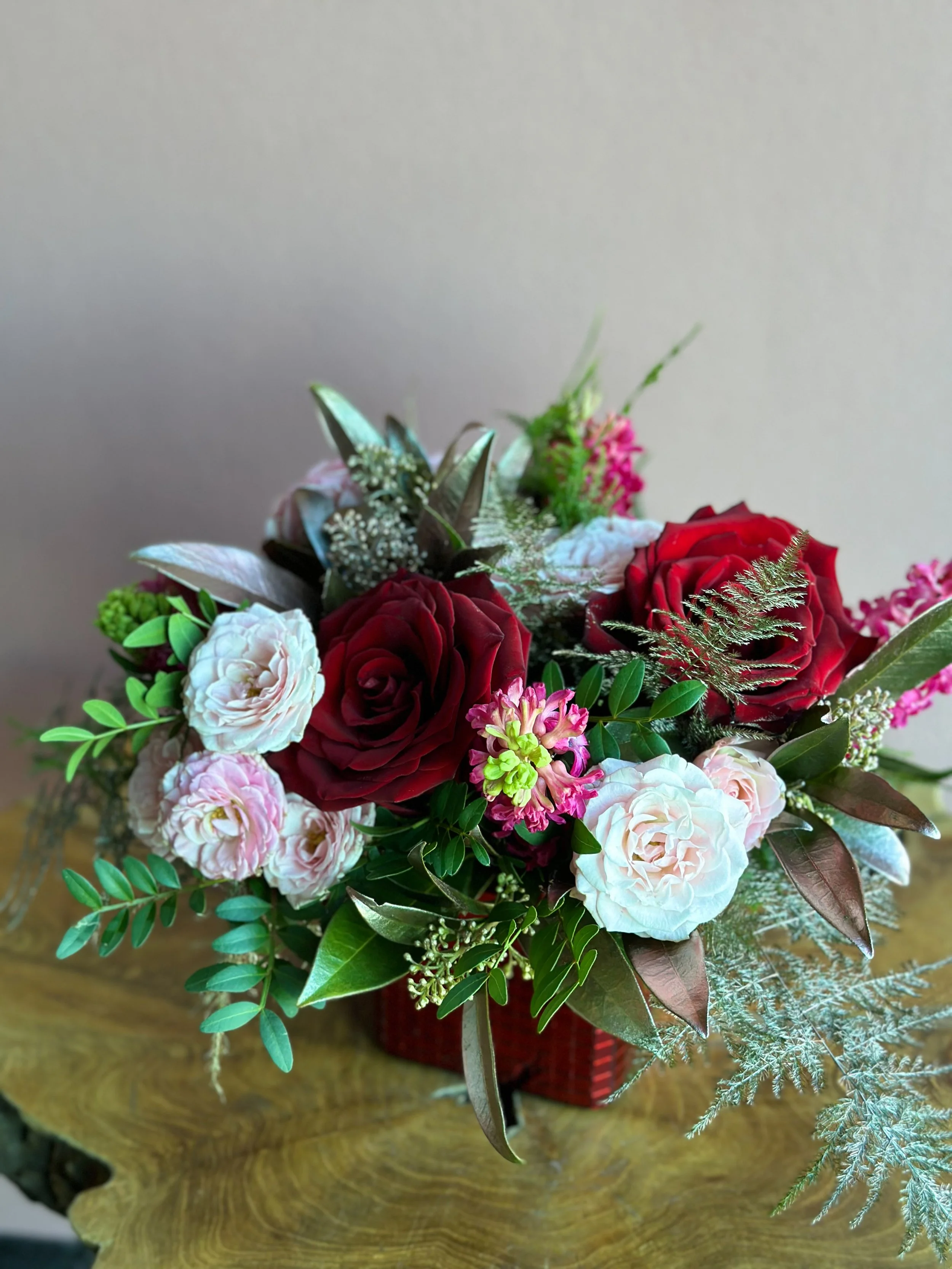 Small Valentine’s Day flower arrangement with red roses, pink tulips, blue accents, and fresh greenery in a red cube vase, available for Edmonton St Albert and Sturgeon County flower delivery.