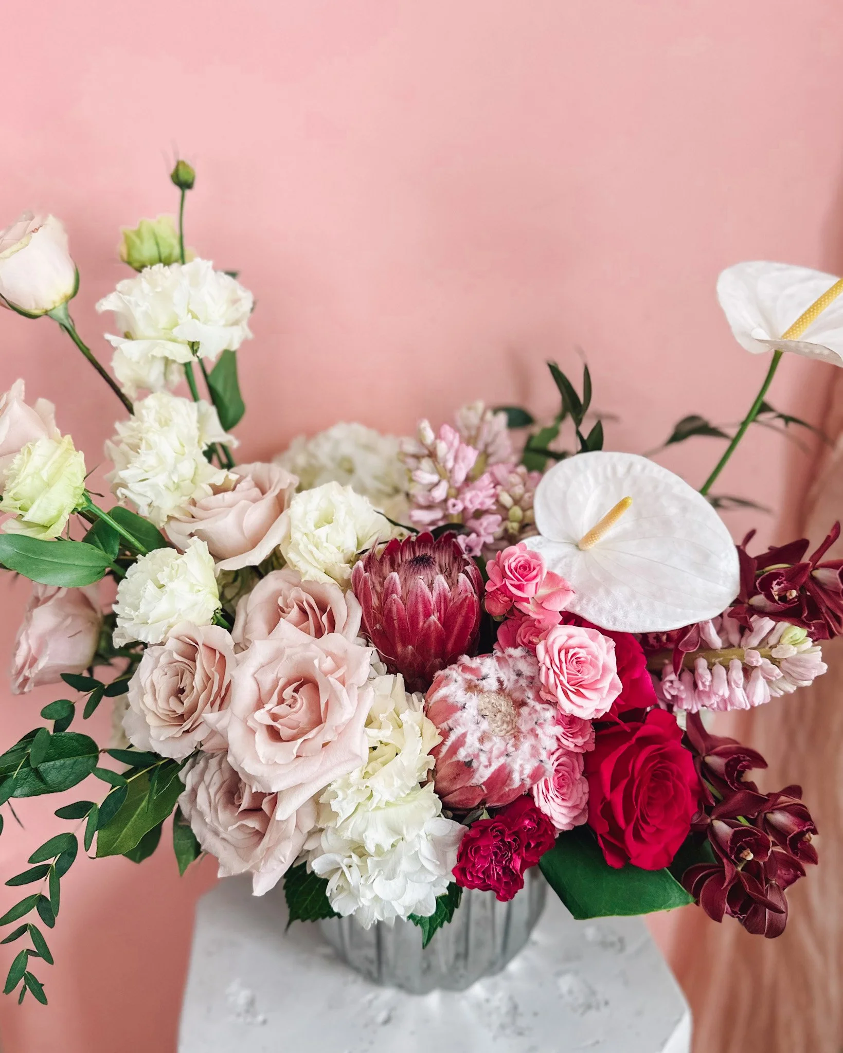 Luxury pink and blush floral arrangement with roses, protea, anthurium and soft greenery in a mirrored vase, available for delivery in Edmonton, St Albert and surrounding areas.