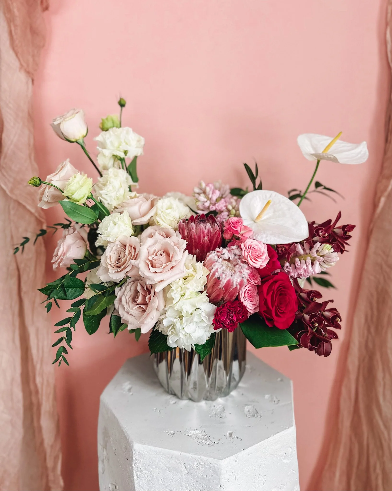 Luxury pink and blush floral arrangement with roses, protea, anthurium and soft greenery in a mirrored vase, available for delivery in Edmonton, St Albert and surrounding areas.