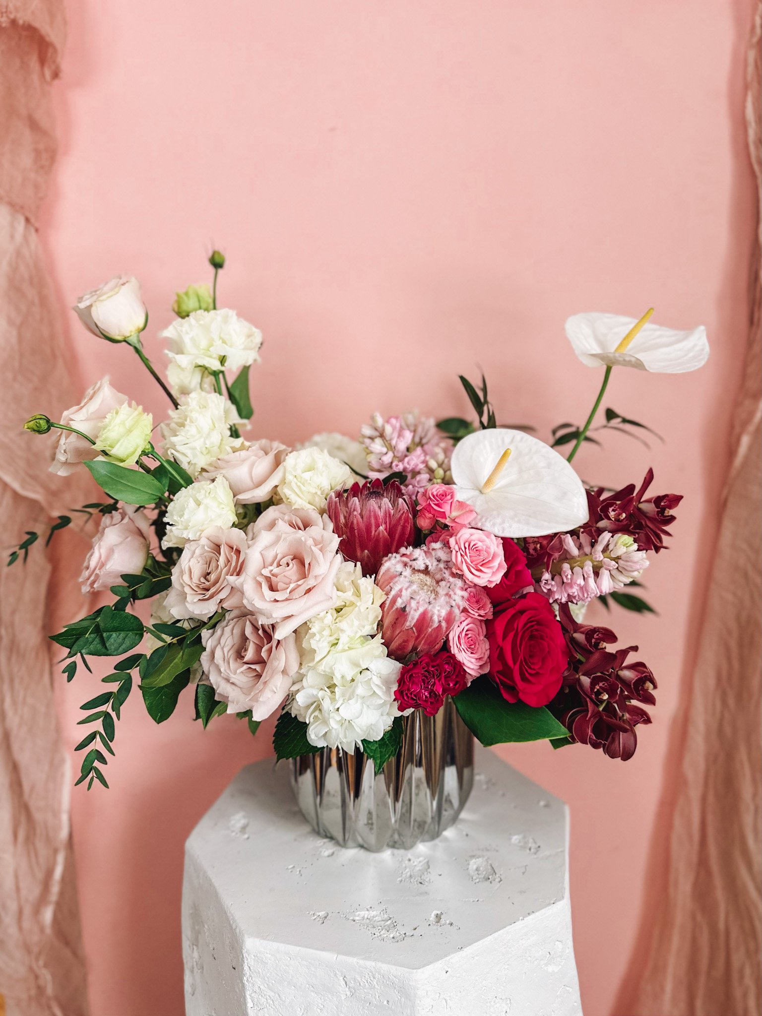 Luxury pink and blush floral arrangement with roses, protea, anthurium and soft greenery in a mirrored vase, available for delivery in Edmonton, St Albert and surrounding areas.