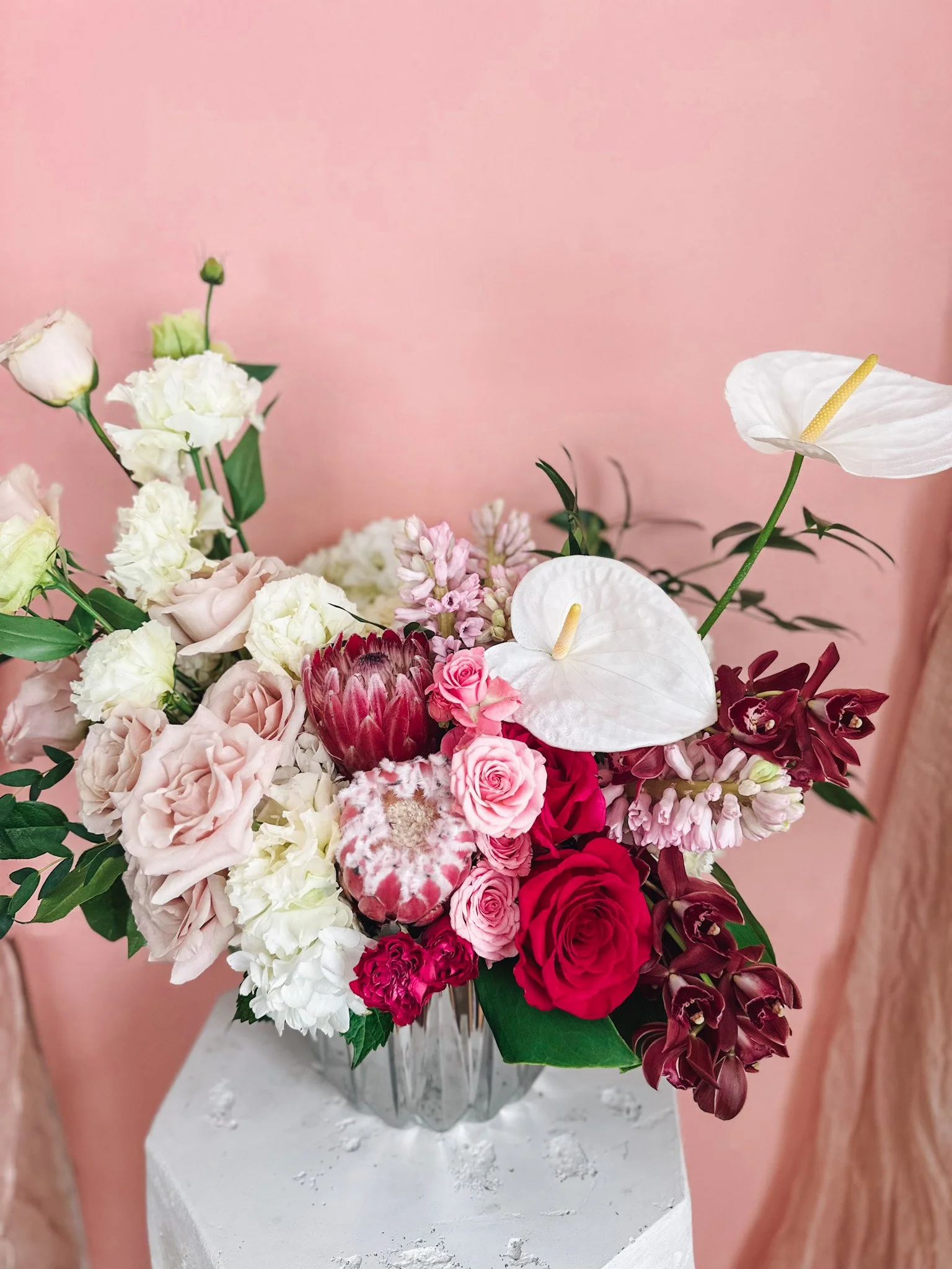 Luxury pink and blush floral arrangement with roses, protea, anthurium and soft greenery in a mirrored vase, available for delivery in Edmonton, St Albert and surrounding areas.