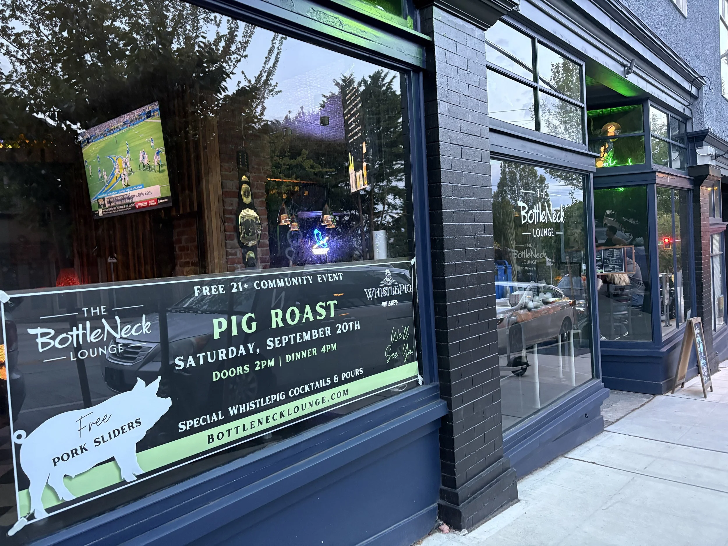 The BottleNeck Lounge building with a banner in the front window advertising the Annual Pig Roast in September