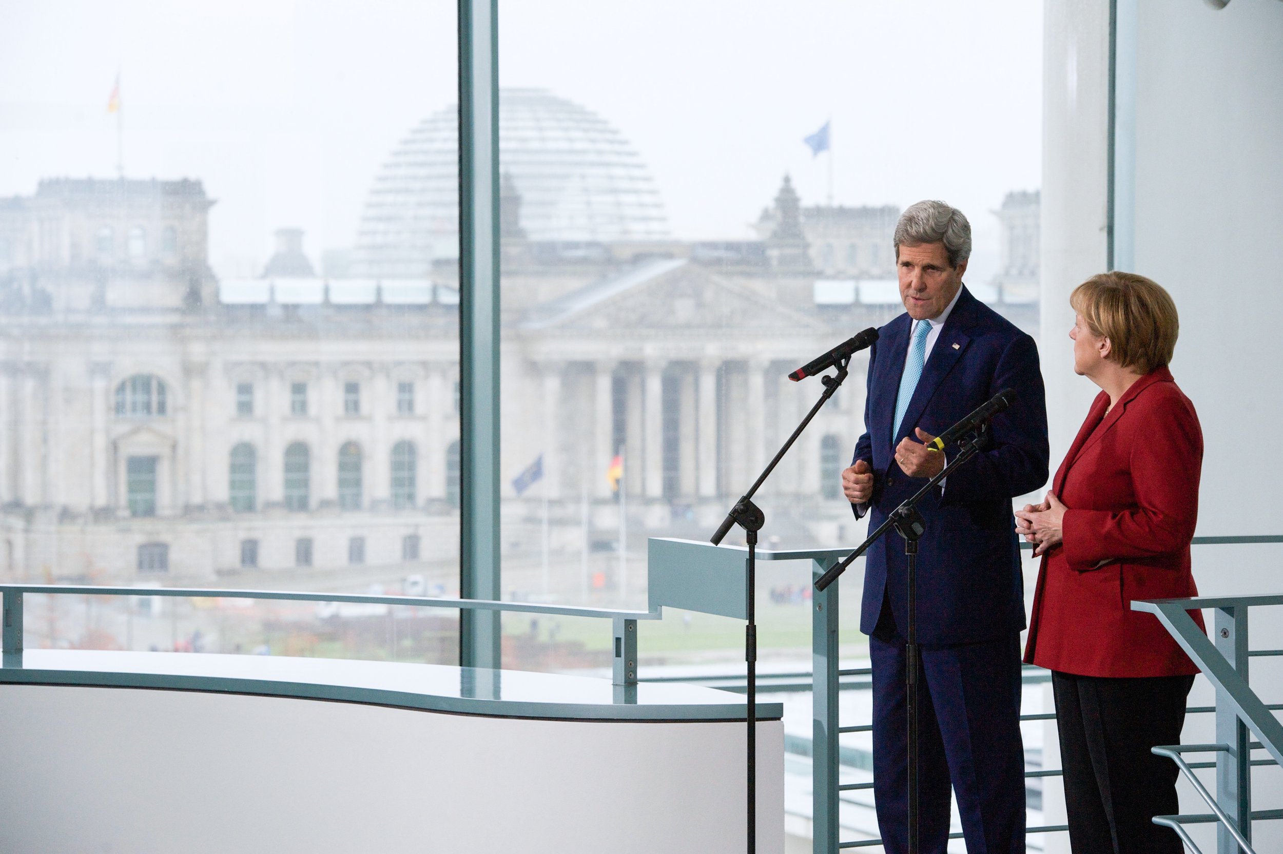  Addressing reporters with German Chancellor Merkel as the Reichstag looms in the background. 