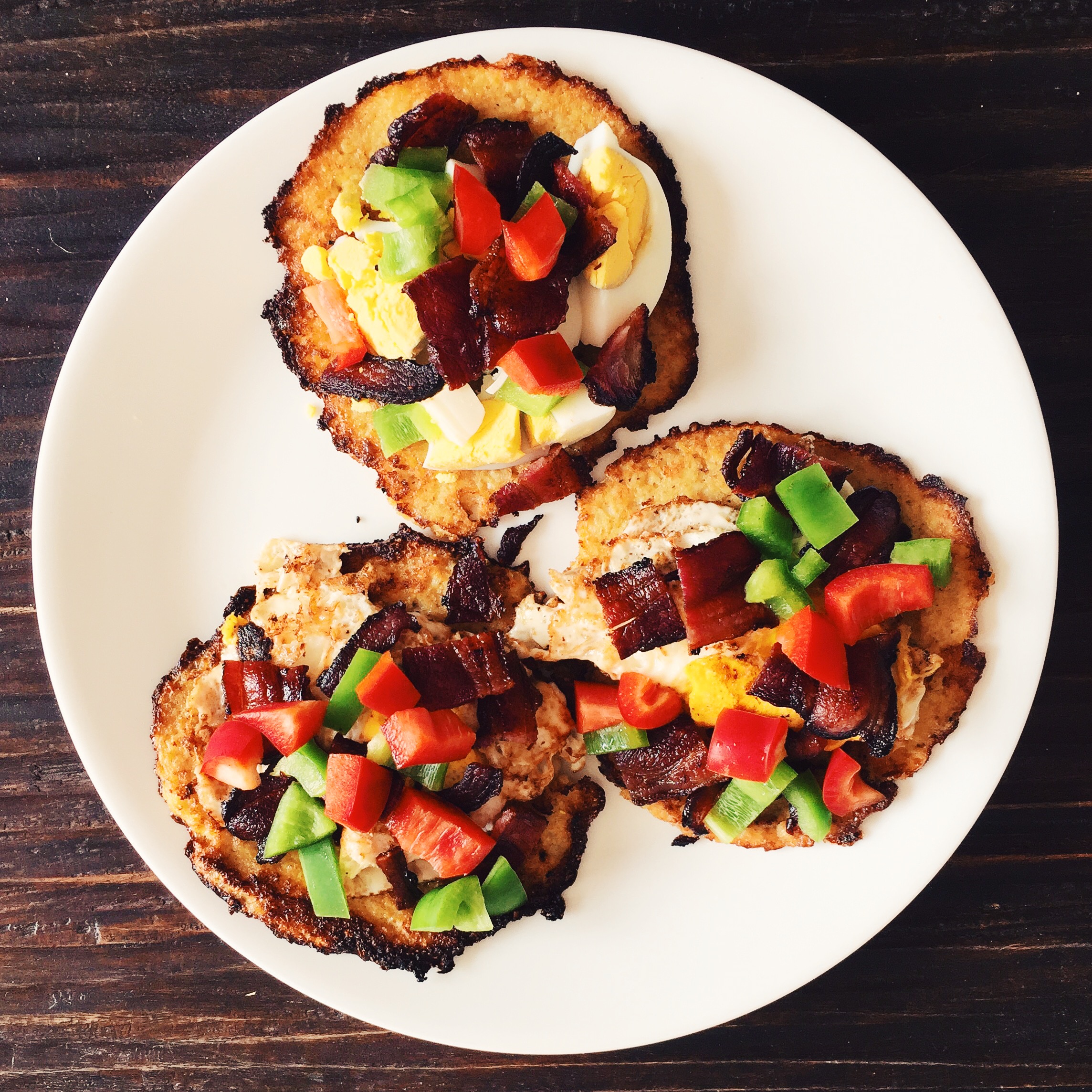 Cauliflower tortilla toped with eggs, bacon, and bell peppers