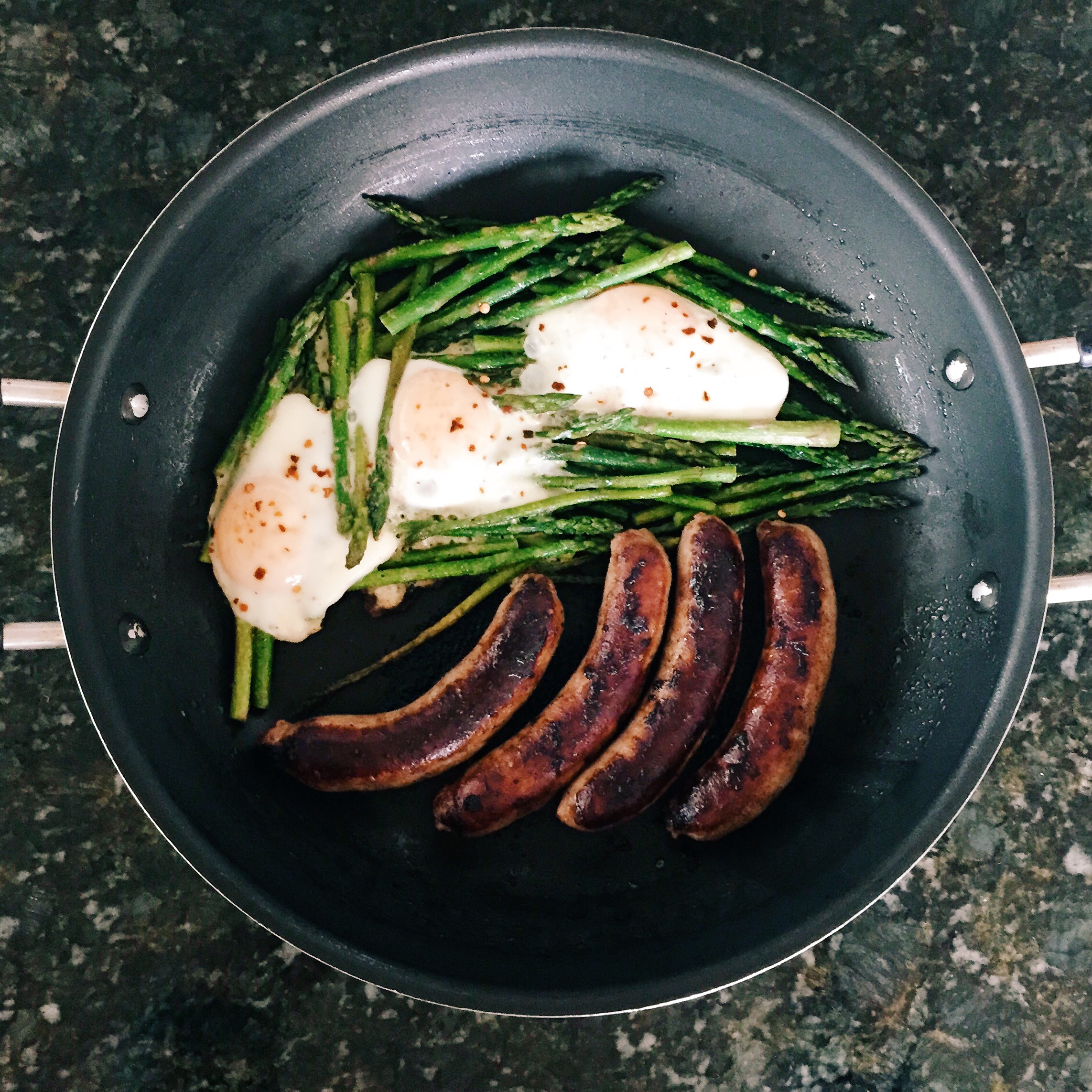 Sausage, asparagus and baked eggs. Cook the sausage first then add asparagus with salt and black pepper and cook for 5 minutes. Crack eggs on top of the asparagus and then broil for 3-5 minutes. Sprinkle red chill pepper on top before serving.