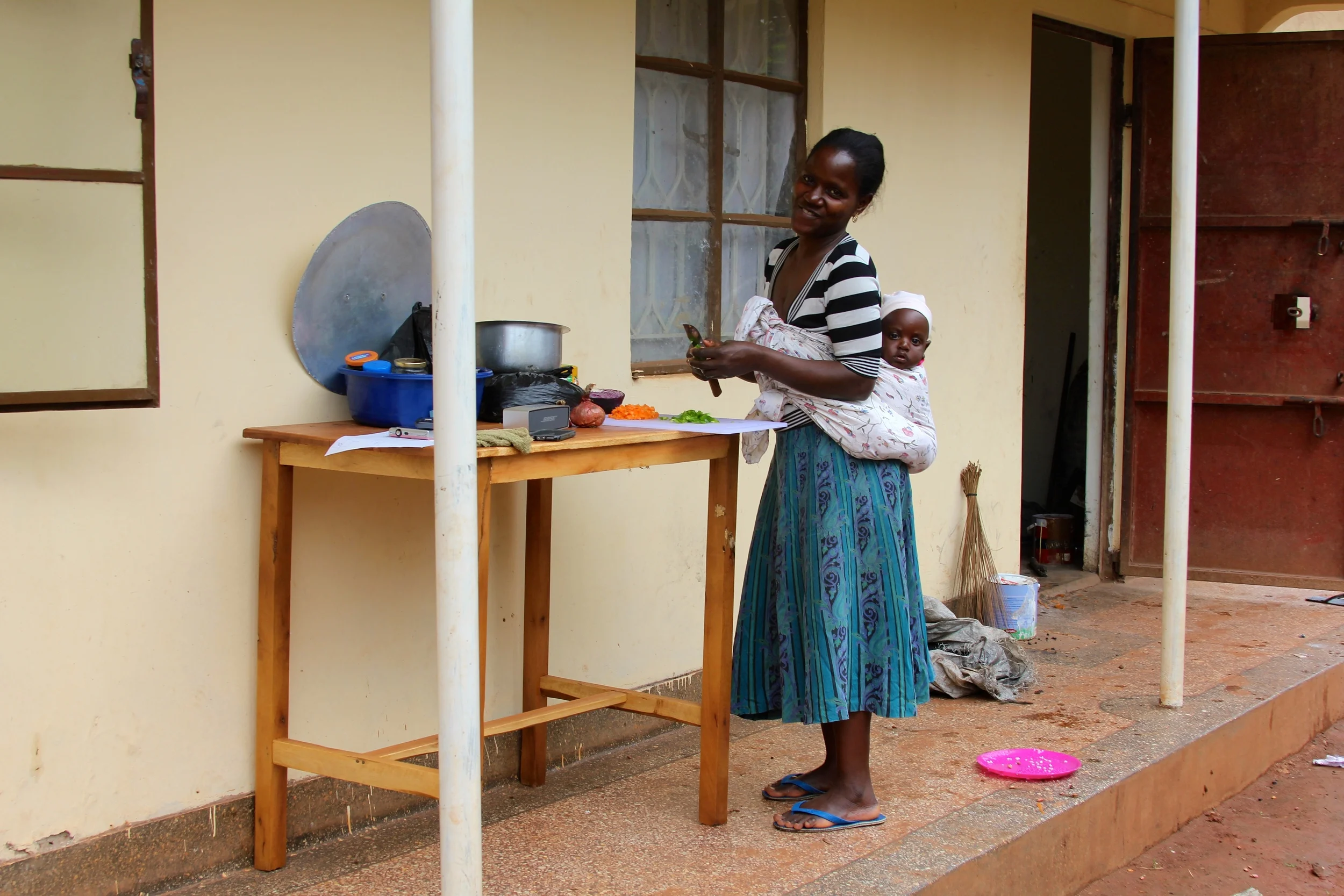 Mama Shaki preparing lunch by cutting carrots, onions and green peppers. 