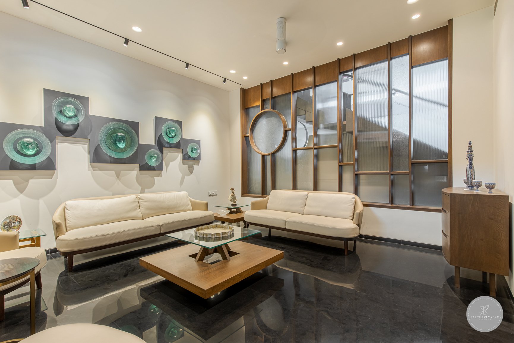best interior photographer in pune bangalore - glass sculpture faces on wall of a living room with glass and wood architecture walls and leather sofas.jpg