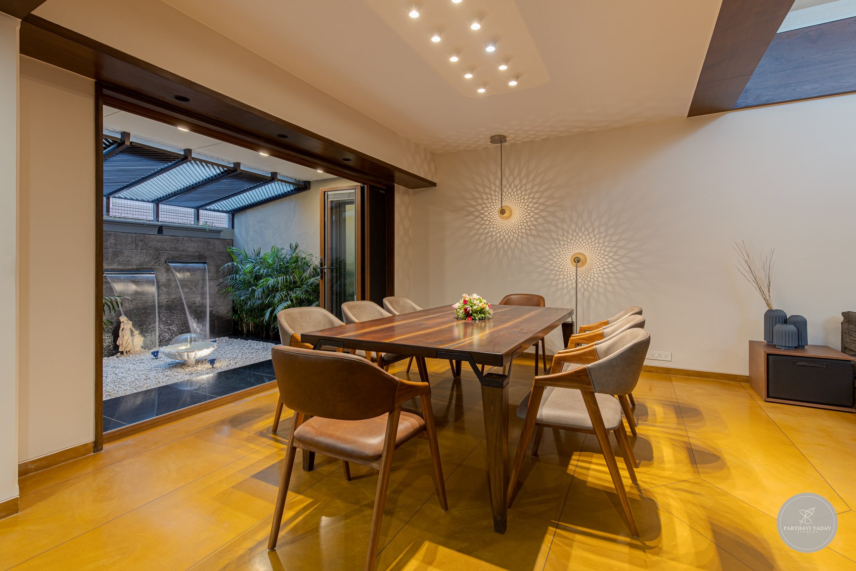 best interior photographer in pune bangalore - award winning lighting in dining space with outdoor fountain and custom wooden dining table and chairs.jpg