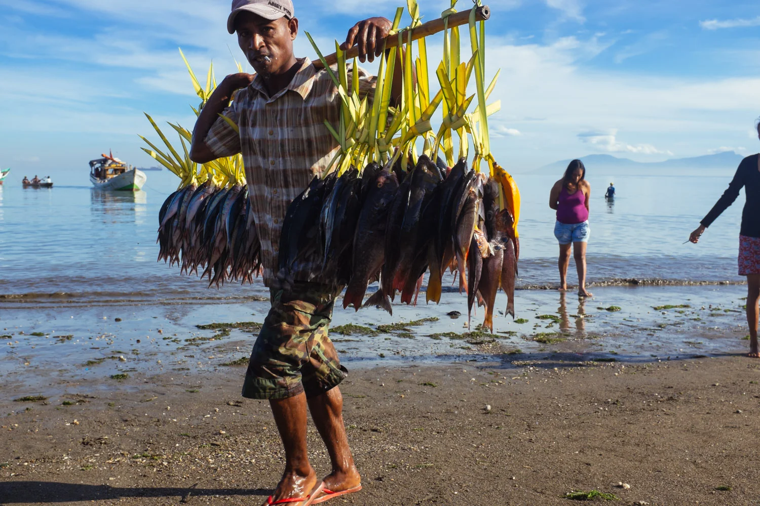A fisherman walking off the ocean on a beach in central Dili
