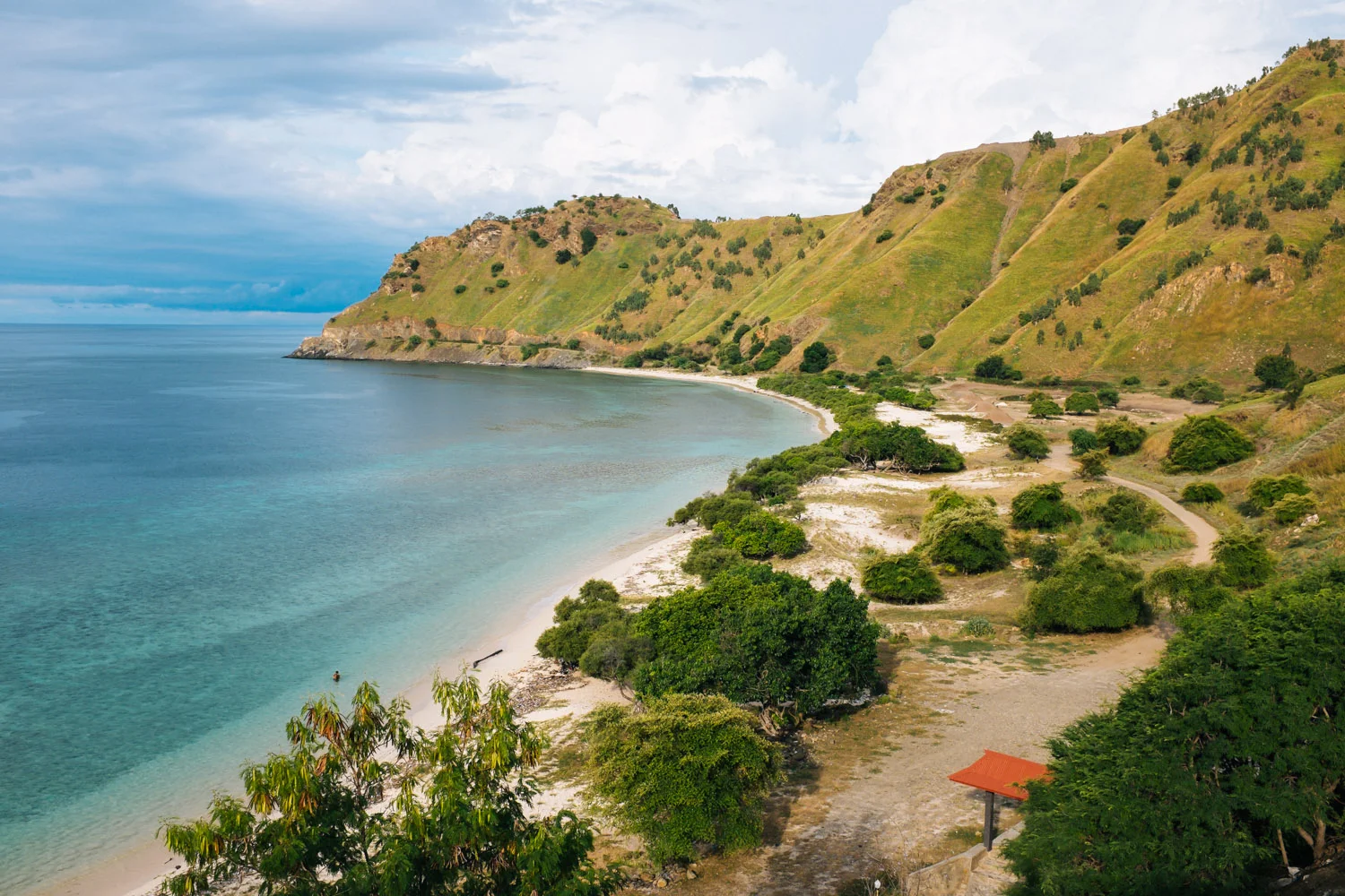 An unspoiled beach surrounded by green mountains in Dili