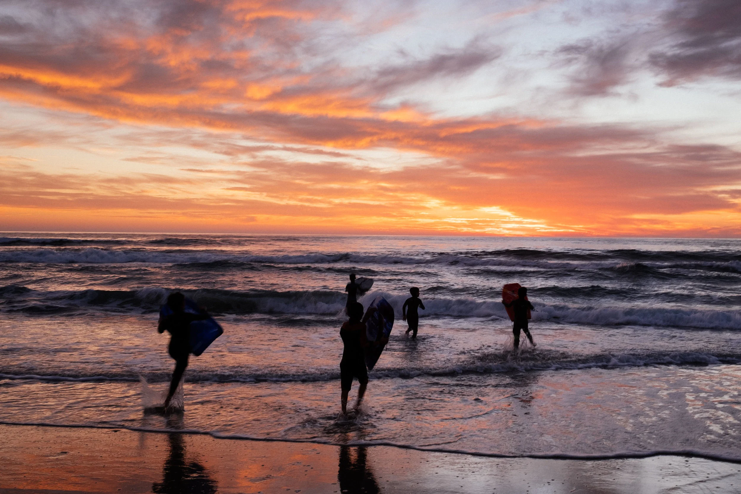 A burning sky and some happy kids enjoying their last waves for the day