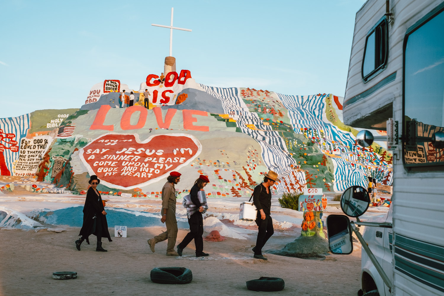 A troupe of gypsies walking by Salvation Mountain, CA