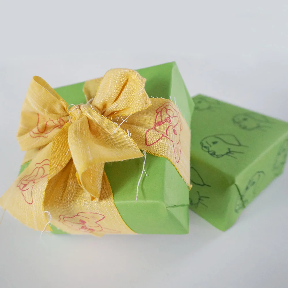 Never find yourself without adorable wrapping when you have colored paper, a scrap of fabric, and a dog portrait stamp .