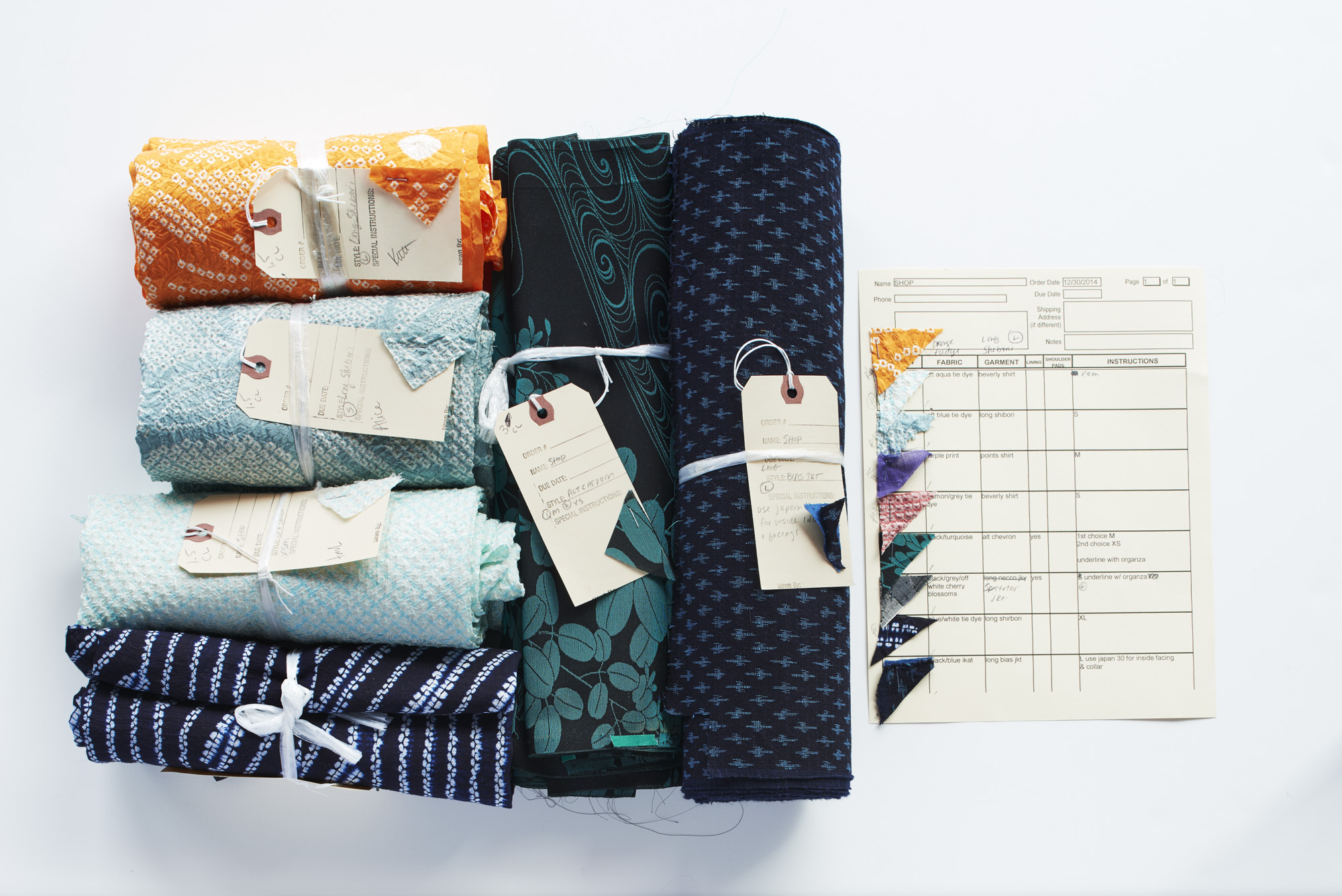 Six vintage kimono fabrics having been taken apart, inspected for flaws and clipped to indicate the garment to be made.
