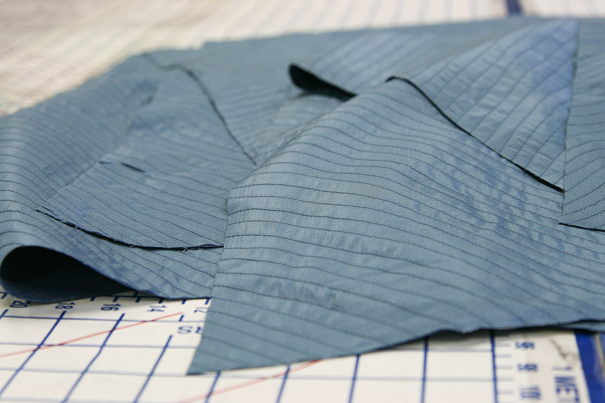 Blue linen is stitched to a lightweight blue silk backing in diagonal rows on the bias.
