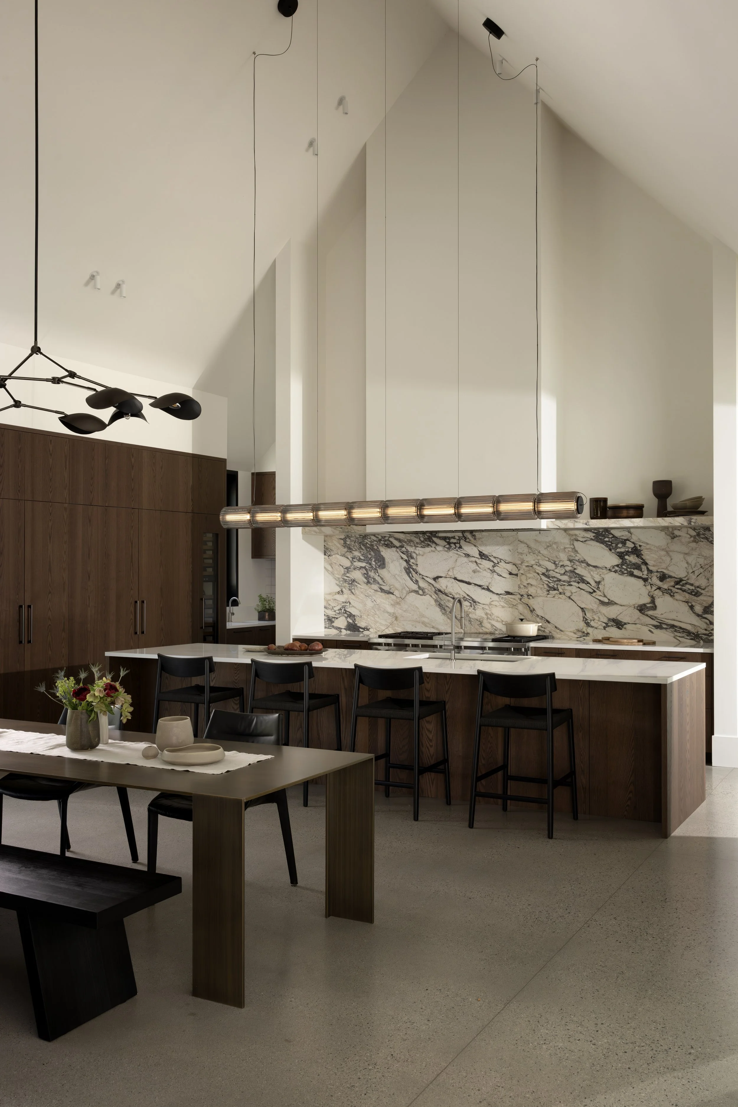 The interiors are designed by Sophie Burke; the kitchen defined by warm millwork in rich wood tones, creating a sense of depth and permanence. A palette of Tuscan-inspired earth tones grounds the space, lending it a relaxed character that feels both
