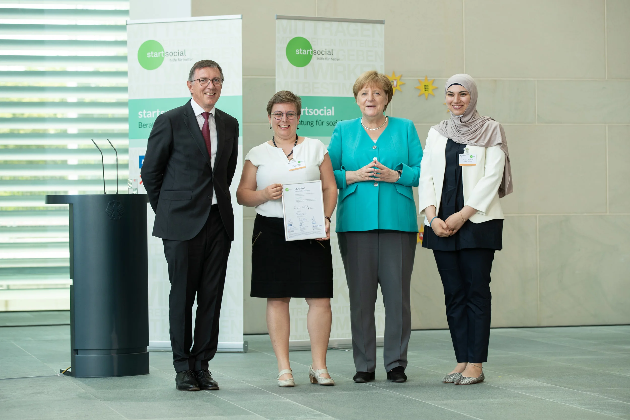 ©startsocial e.V./Thomas Effinger von links nach rechts: Dr. Dieter Düsedau (Gründer von startsocial e.V.), Nina Liebhaber (TranslAid), Bundeskanzlerin Angela Merkel (Schirmherrin von startsocial e.V.), Sausan Jindawi (TranslAid)