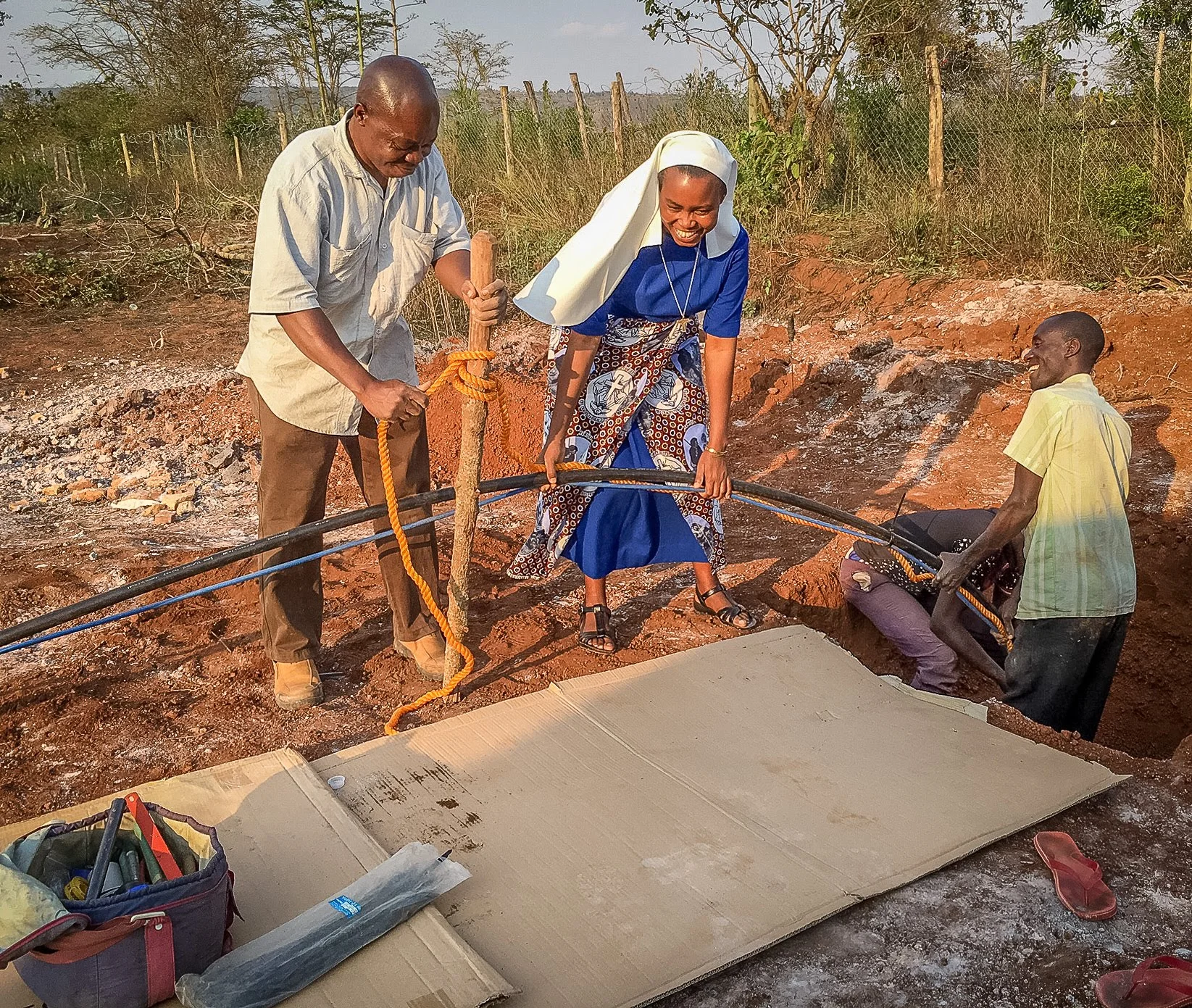 Sr. Dativa and others help send the pump down to the well.