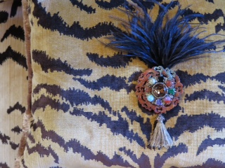 Detail of velvet tiger pillow from the Tyger Tyger Collection with aigrette of carved coral jade with an overlay of semi-precious stones and ostrich tuft flourish