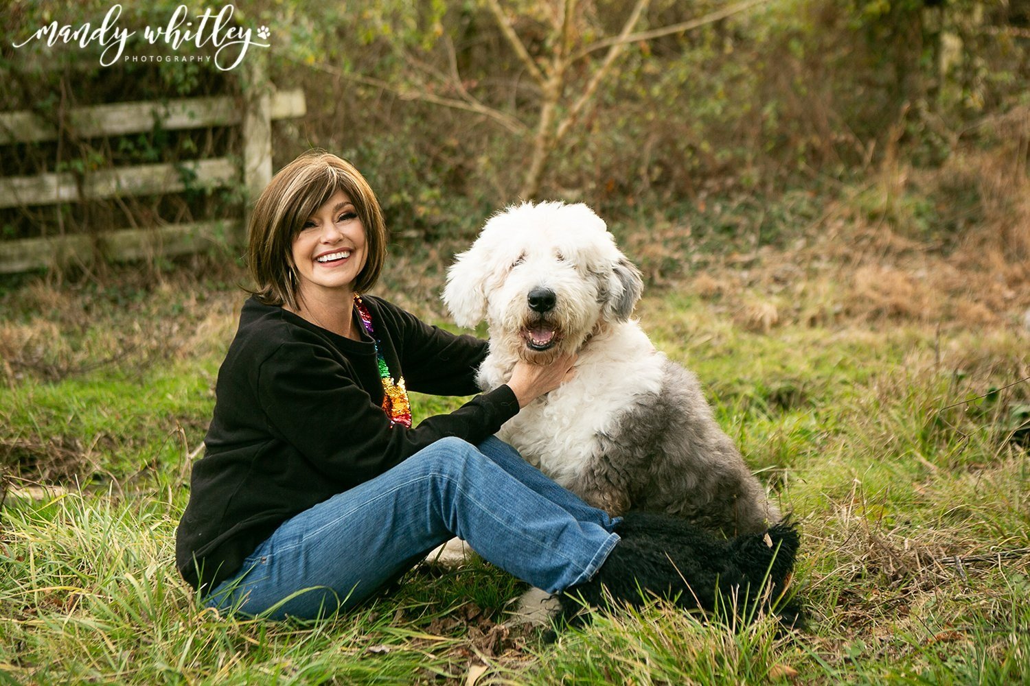 Woman and Old English Sheepdog looking at camera in field