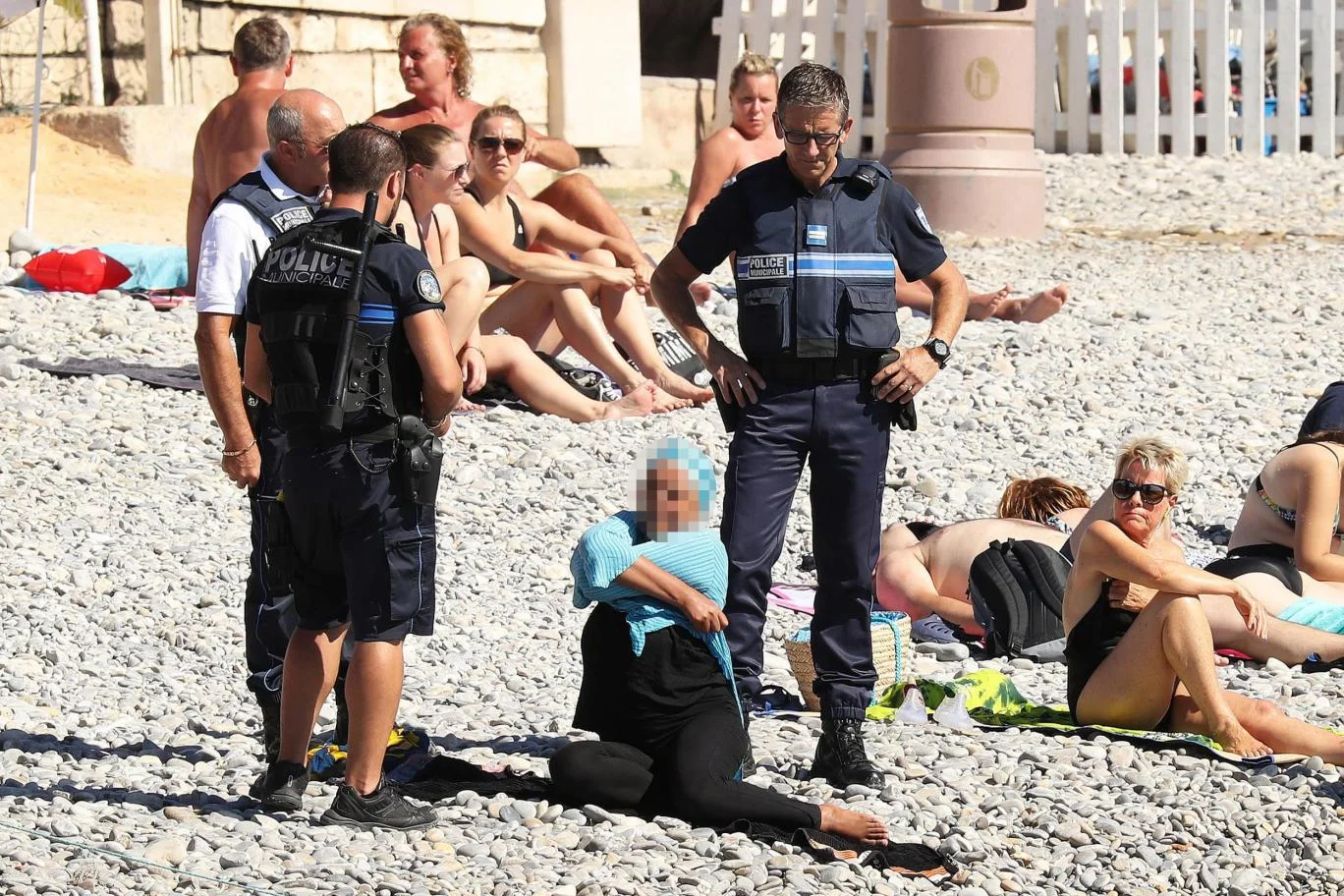 Woman being undressed by police in public in Cannes. Credit: The Independent
