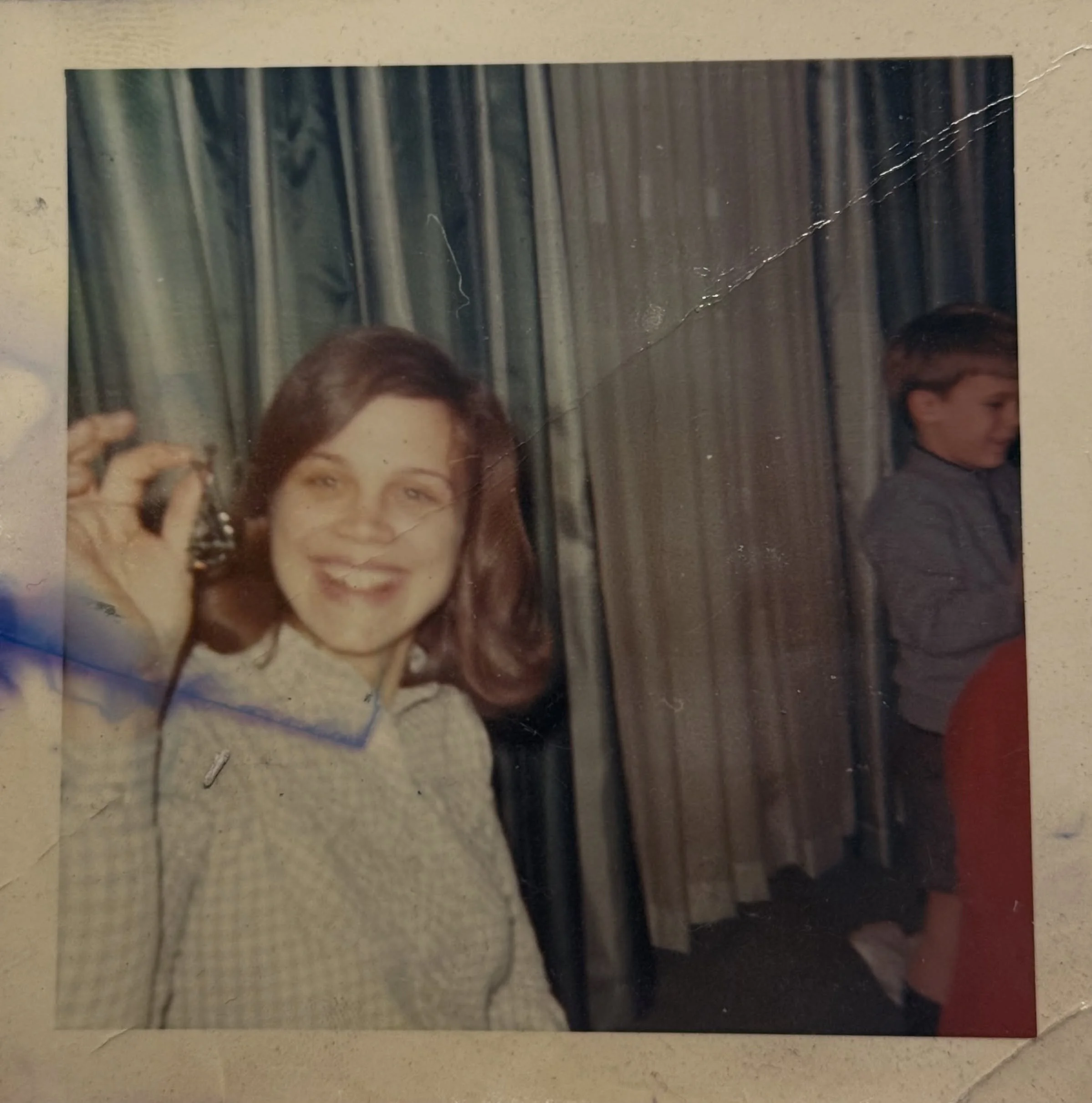 She always held it together for the whole clan of seven. A juggler and a singer of songs.  A balancing act for sure. And that smile. And always up to listening to each and every one of us. Mom is 23 here. That&rsquo;s me in the background.