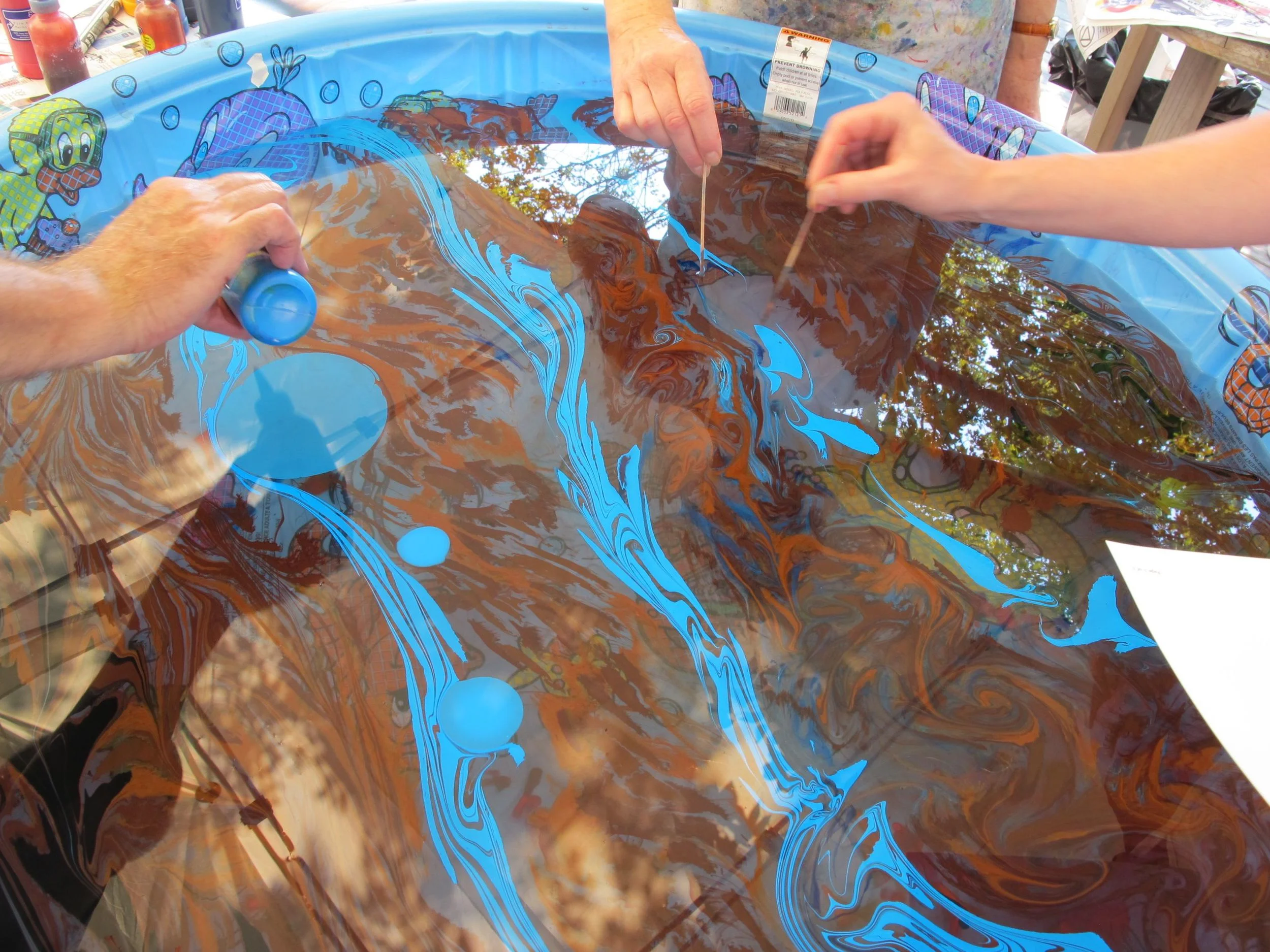 At one of the Notebook's summer workshops, we marbleized paper and fabric under the tutelage of artist Shira Singer. Here we're floating paint on the surface of thickened water. We then set a large circle of paper on top of the paint, removed the paper and rinsed it in the first step toward creating the planet Jupiter.