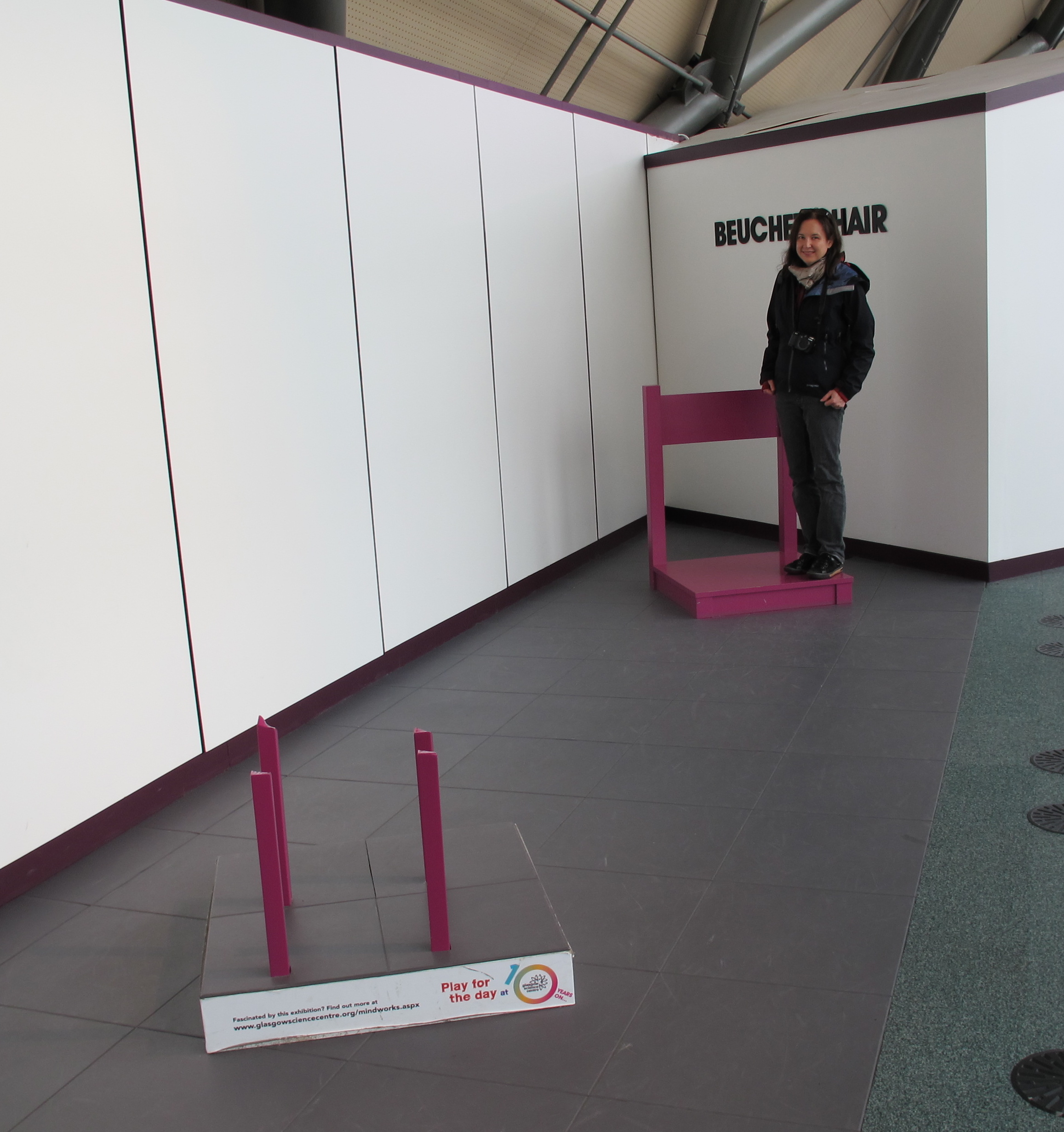 A camera shoots the image from a spot outside the left edge of this picture, with the legs and the chairback lined up to create the illusion. In our photo, Pamelia stood closer to the camera, by the two chair legs, while I stood on the seat in back, making her appear larger.