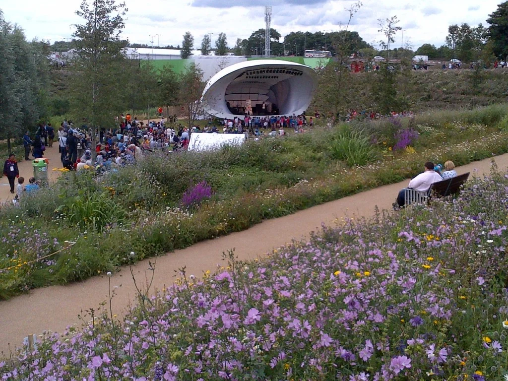 On a stage in the wildflower-filled Olympic park, that’s Wenlock the mascot entertaining kids.