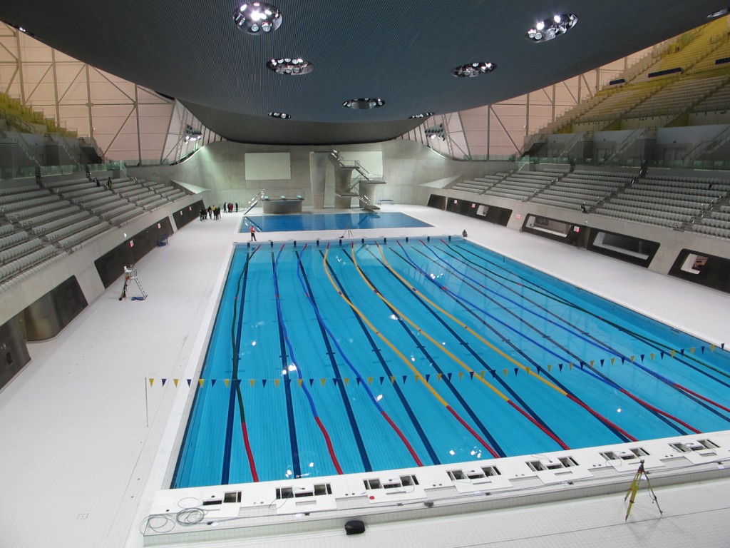 The $421 million aquatics center was designed by Iraqi-born architect Zaha Hadid (a woman) and sits near the Olympic stadium and the velodrome. This is what the place looked like last fall when I and other international journalists toured it and other London Olympic venues. One woman reporter in our group dipped her finger in the diving pool (the pool in back) before being scolded. In case you’re wondering what Michael Phelps, Ryan Lochte and other swimming stars will feel when they dive in, the water temperature of the pool will be kept at 78.8 degrees Fahrenheit (26 degrees Celsius) for competition.