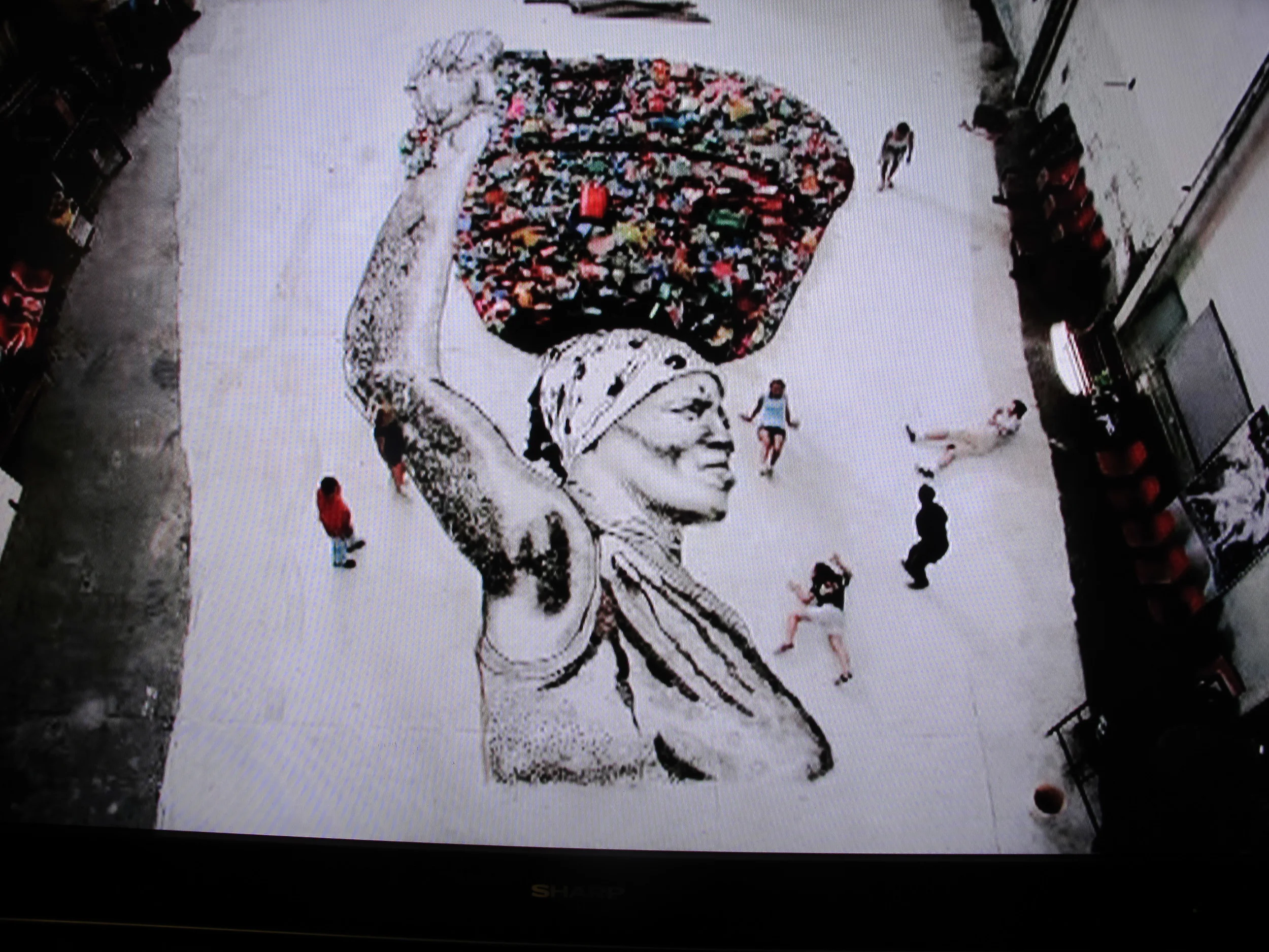 This portrait—a floor-sized blowup of a photo by Vik Muniz of one of the Rio women—was turned into art by the trash-pickers themselves, using landfill junk to outline and, in a sense, paint the image.