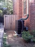 Rain barrel placed discreetly behind a historic home. Source.