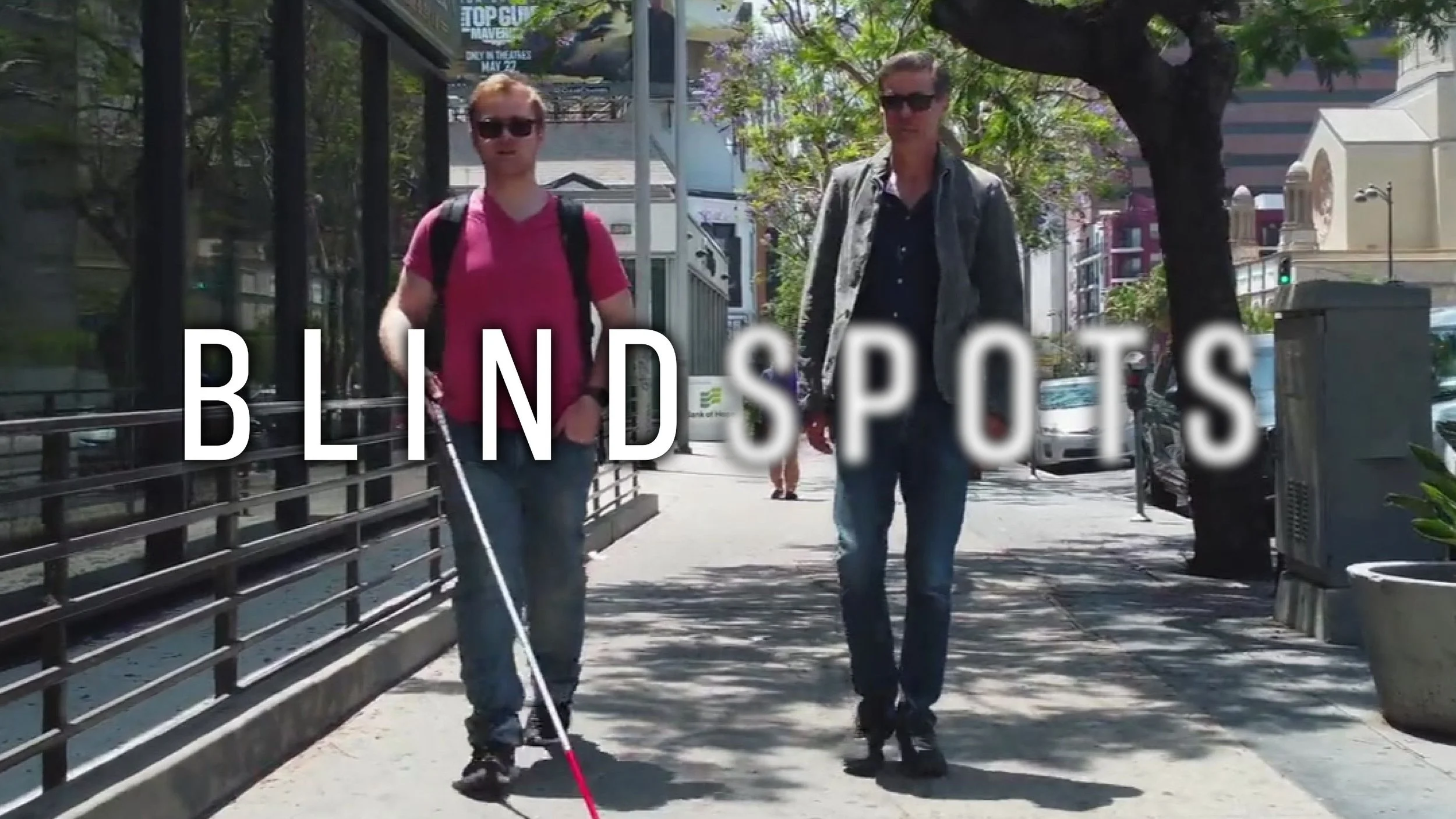 James Rath and Roy Samuelson walk down a street in Los Angeles. The Blindspots logo is overlaid. Spots is slightly blurred.