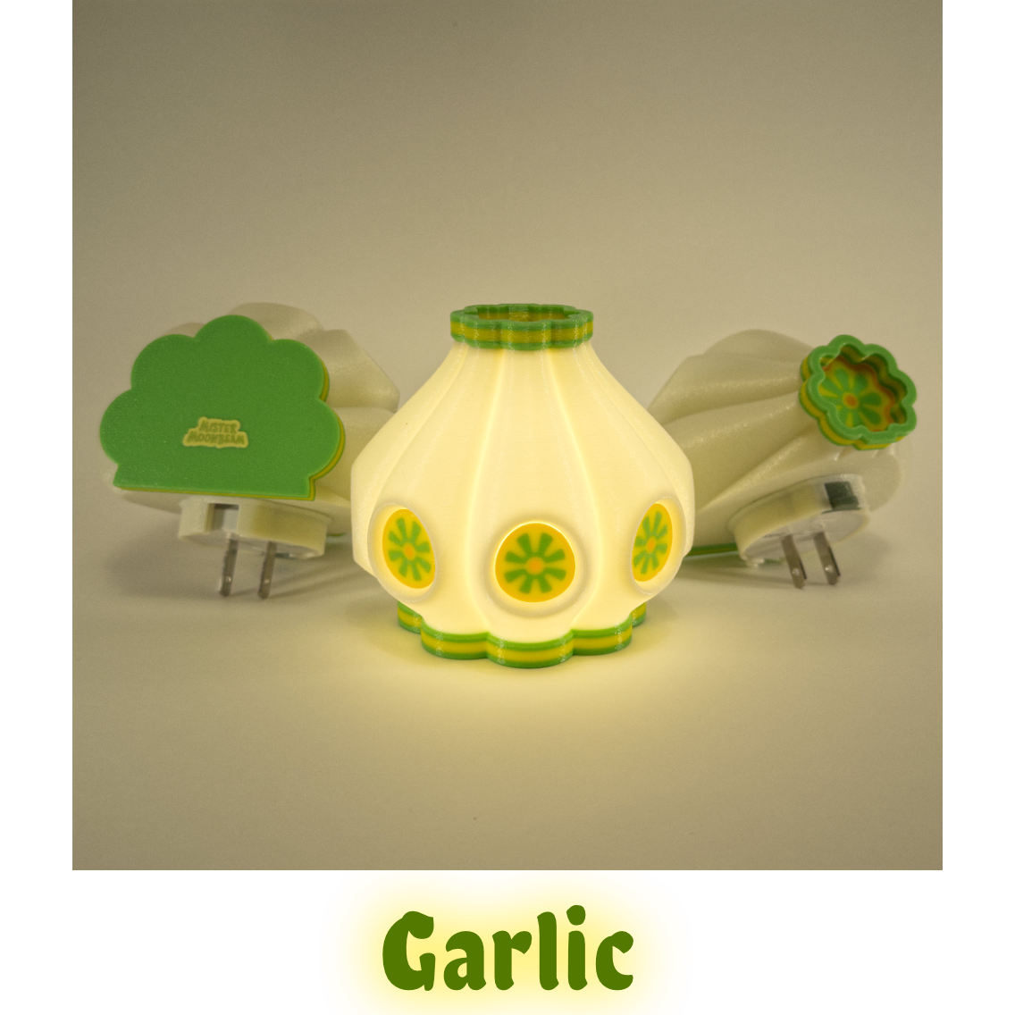 Three Garlic night lights in citrus yellow and green, one glowing, with plug prongs visible