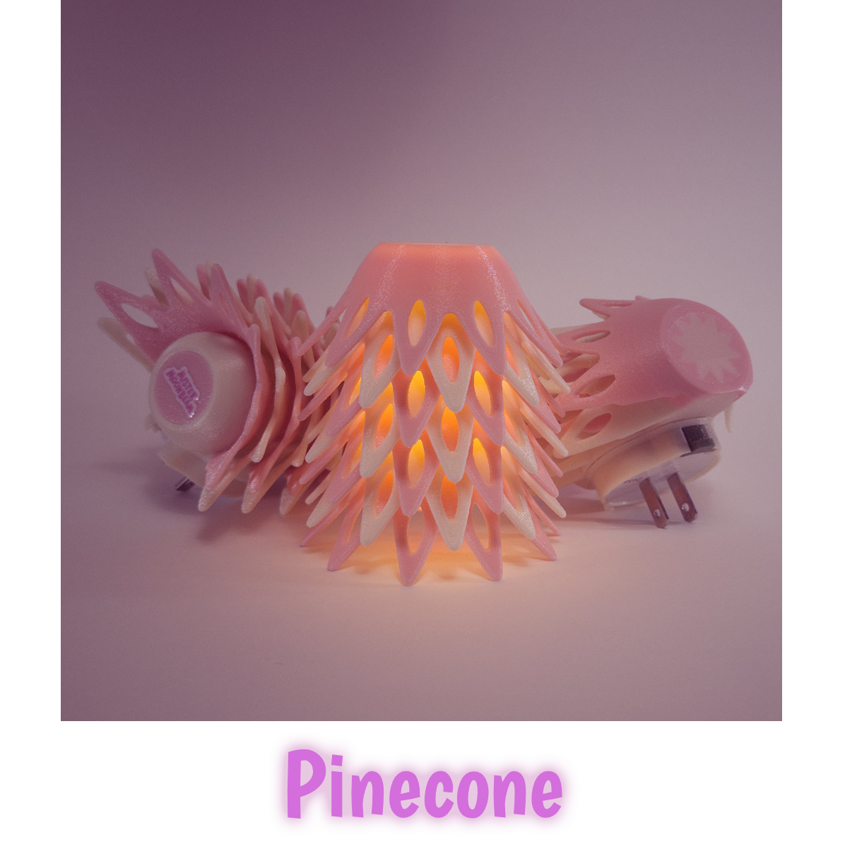 Three Pinecone night lights in pink, one glowing, with plug prongs visible