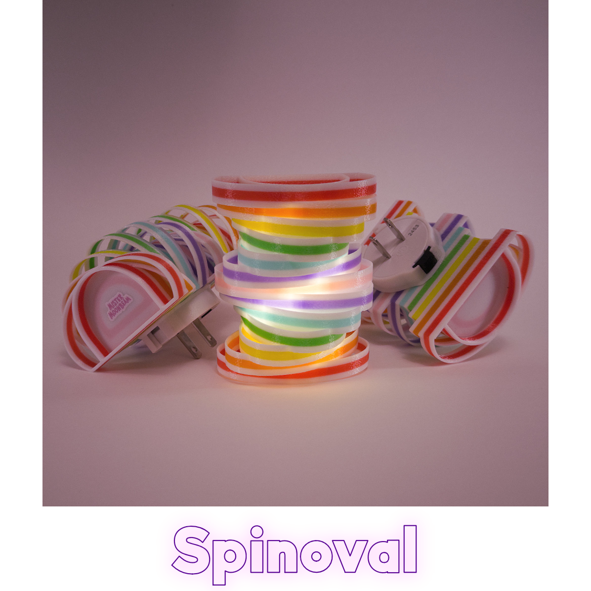 Three Spinoval night lights in rainbow stripes, one glowing, with plug prongs visible