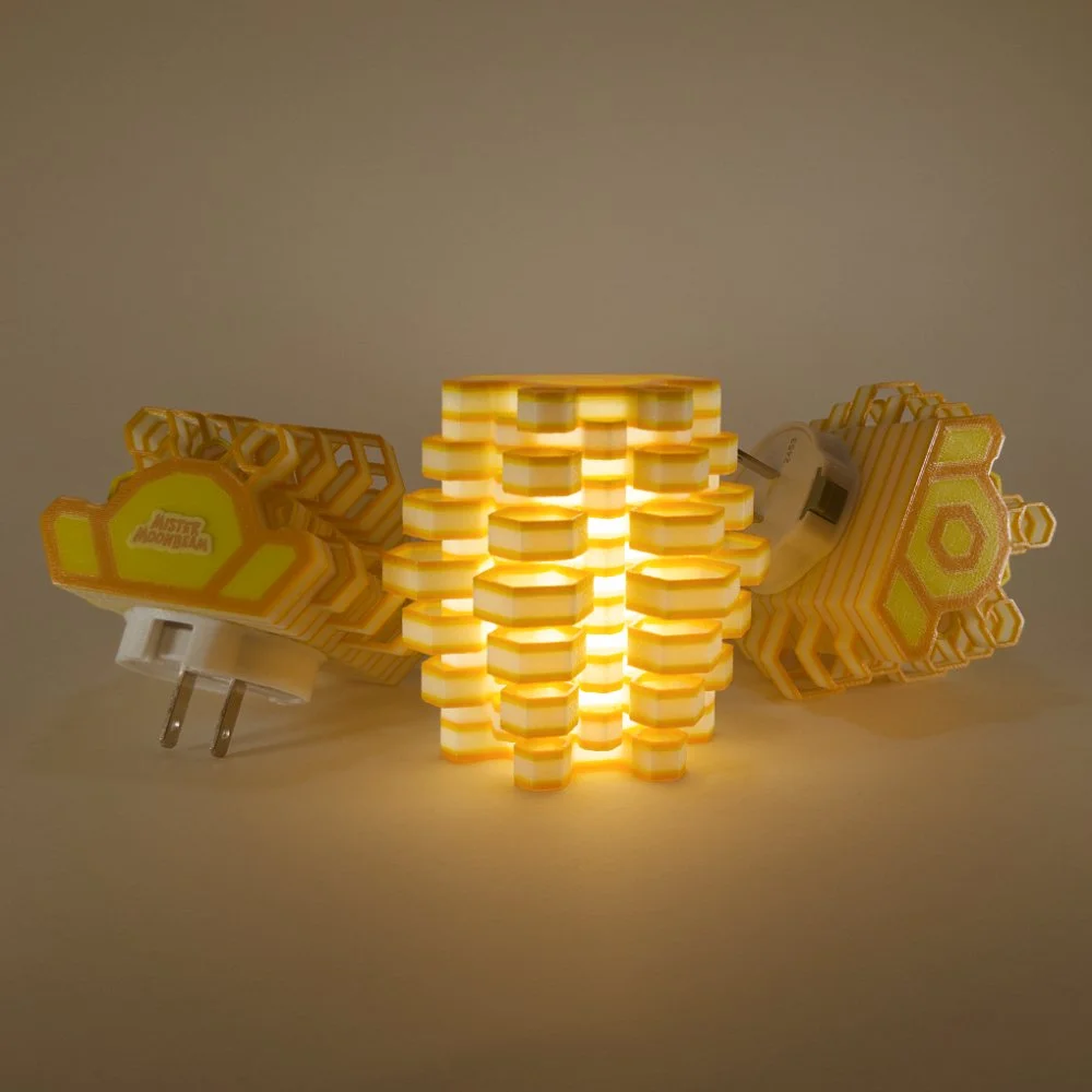 Three Hexy night lights in orange and yellow, glowing