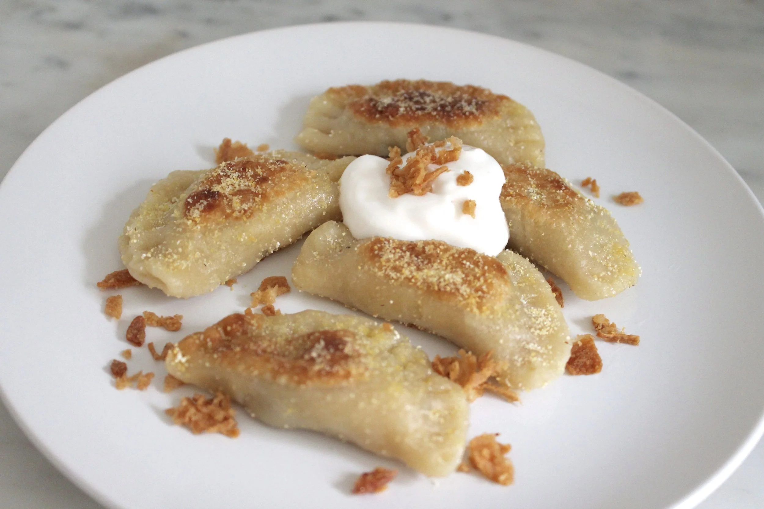Potato, mushroom, and fried onion pierogi pan fried in brown butter and white cornmeal. Topped with sour cream and fried onions. 