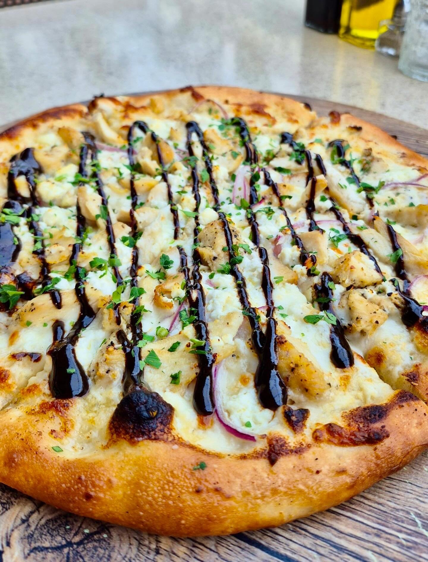 Winter ❄️ Weekly Pizza Special🍕: Garlic Cream&ndash;Sauced Pizza stacked with Roasted Garlic, Grilled Chicken, Red Onion, and Feta, kissed with a Black Garlic Gastrique and showered in fresh Parsley
