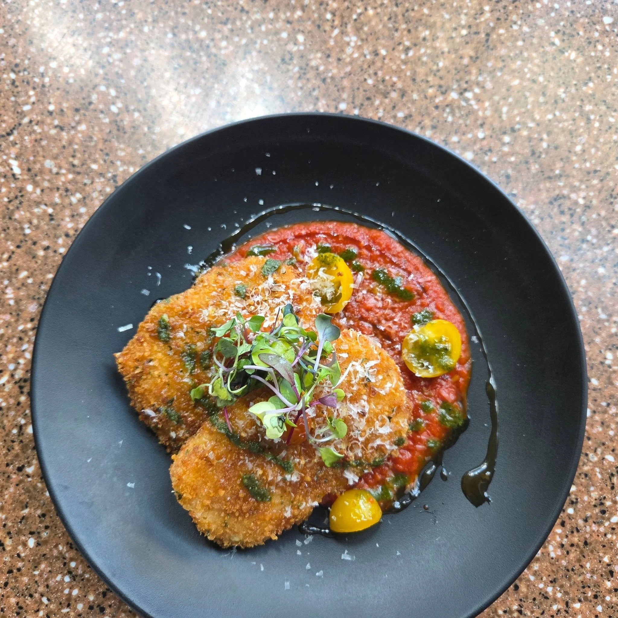 Crispy, golden Panko-Crusted Risotto Cakes filled with mozzarella and bell peppers, served over marinara and finished with marinated cherry tomatoes, lemon gastrique, Parmesan, and microgreens.
Rich, bright, and perfect to share.
