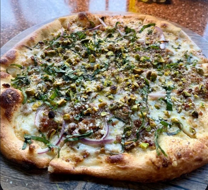 MAY PIZZA SPECIAL: PISTACHIO BIANCO
House-made dough, garlic cream sauce, roasted garlic, fennel 
sausage, red onions, savory pistachios, basil, and lemon zest