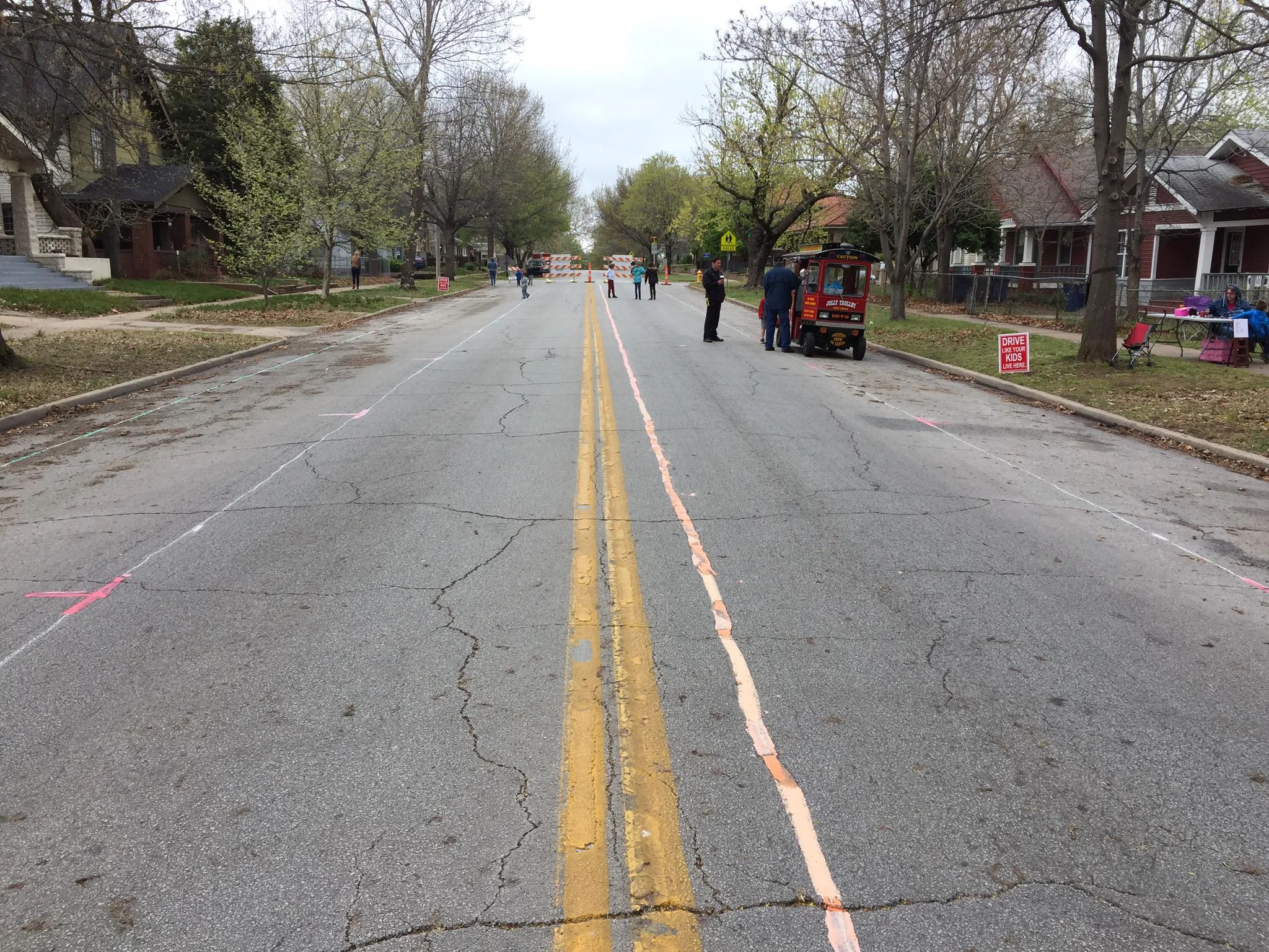 North Denver Avenue as seen with chalk imaging a new travel lane setup. From left to right in the photo, the green line nearest the west curb marks the bicycle lane, the white line with red markings denotes the off-curb parking lane, the orange chalk line to the right of the existing center line marks the new center line between two 10-foot-wide travel lanes, and the last white line with red markings shows the on-curb parking lane on the east curb. (Photo © 2017 Brian Parker)