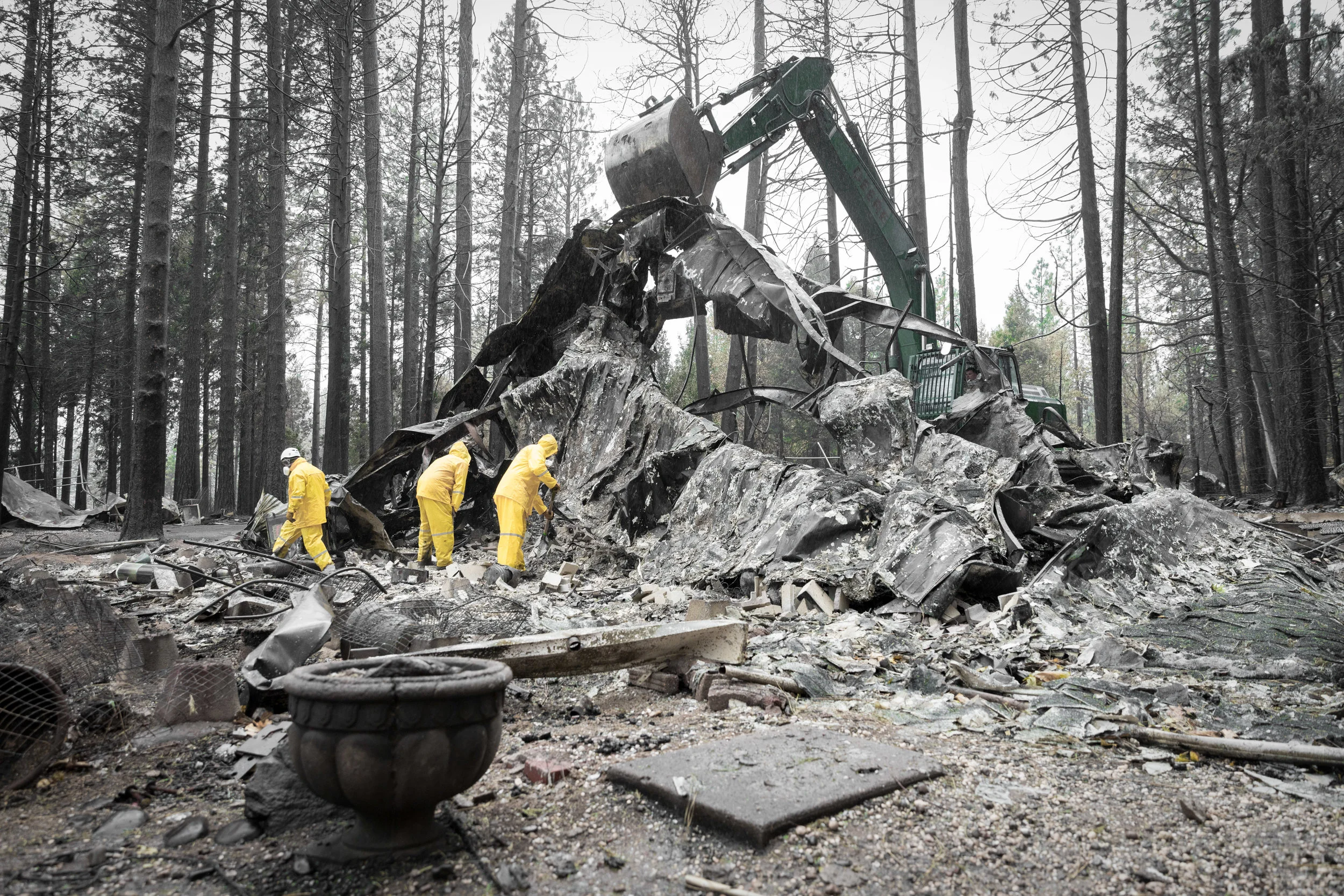 A National Guard excavator lifts the frame of a charred mobile home while rescuers search in Concow, CA — November 21st, 2018