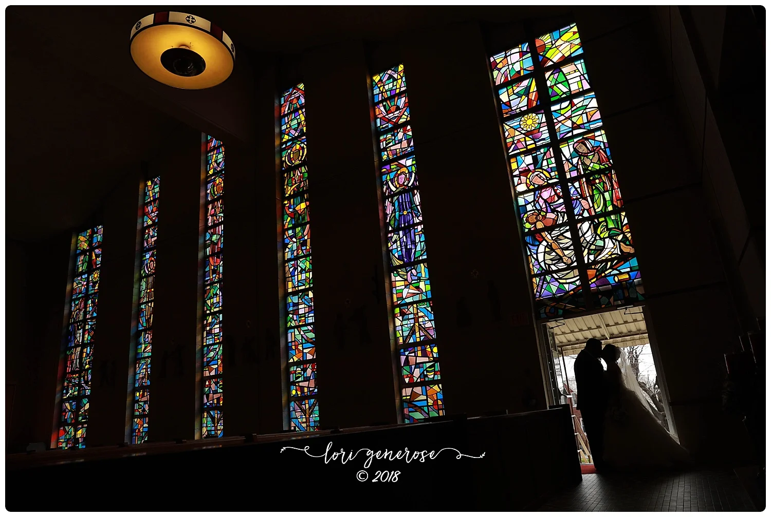 brideandgroomposingbybeautifulstainedglasswindowsinchurchlgphotography.jpg