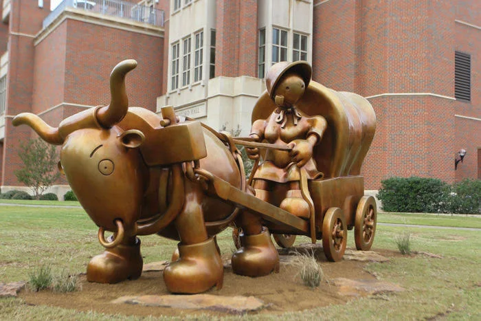The statue by Tom Otterness sits outside of Gaylord College. ( OU Daily, 2018 )