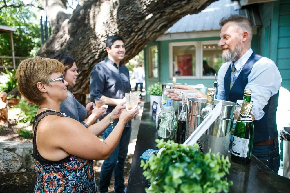 A bartender pouring for guests under the trees