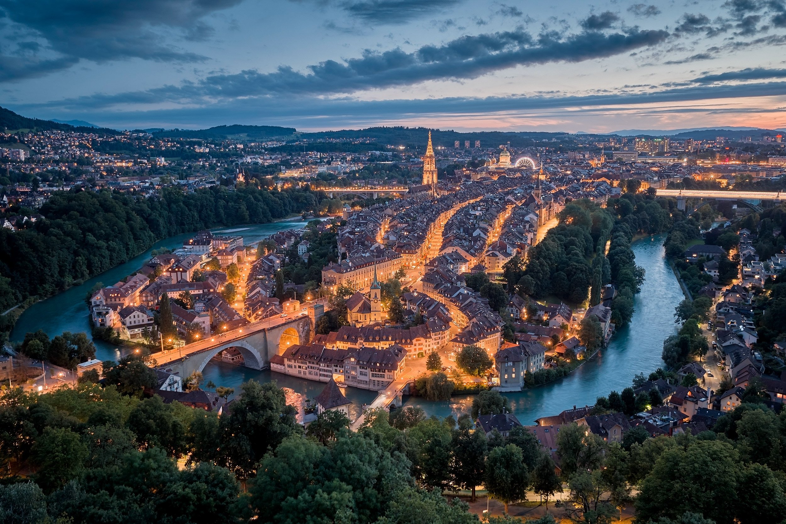  Panorama der Altstadt von Bern bei Abenddämmerung – die Aare umfließt die historische Altstadt mit dem Berner Münster im Zentrum. Fotografiert vom Rosengarten aus, zeigt das Bild die warme Lichtstimmung und die einzigartige Atmosphäre der Schweizer 