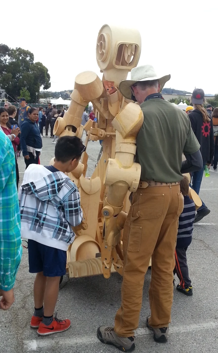 This guy is showing some kids the finer points of his fully articulated wooden robot suit.